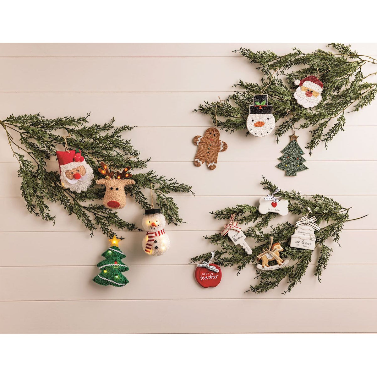 Decorative Christmas ornaments on green branches against a light wooden background