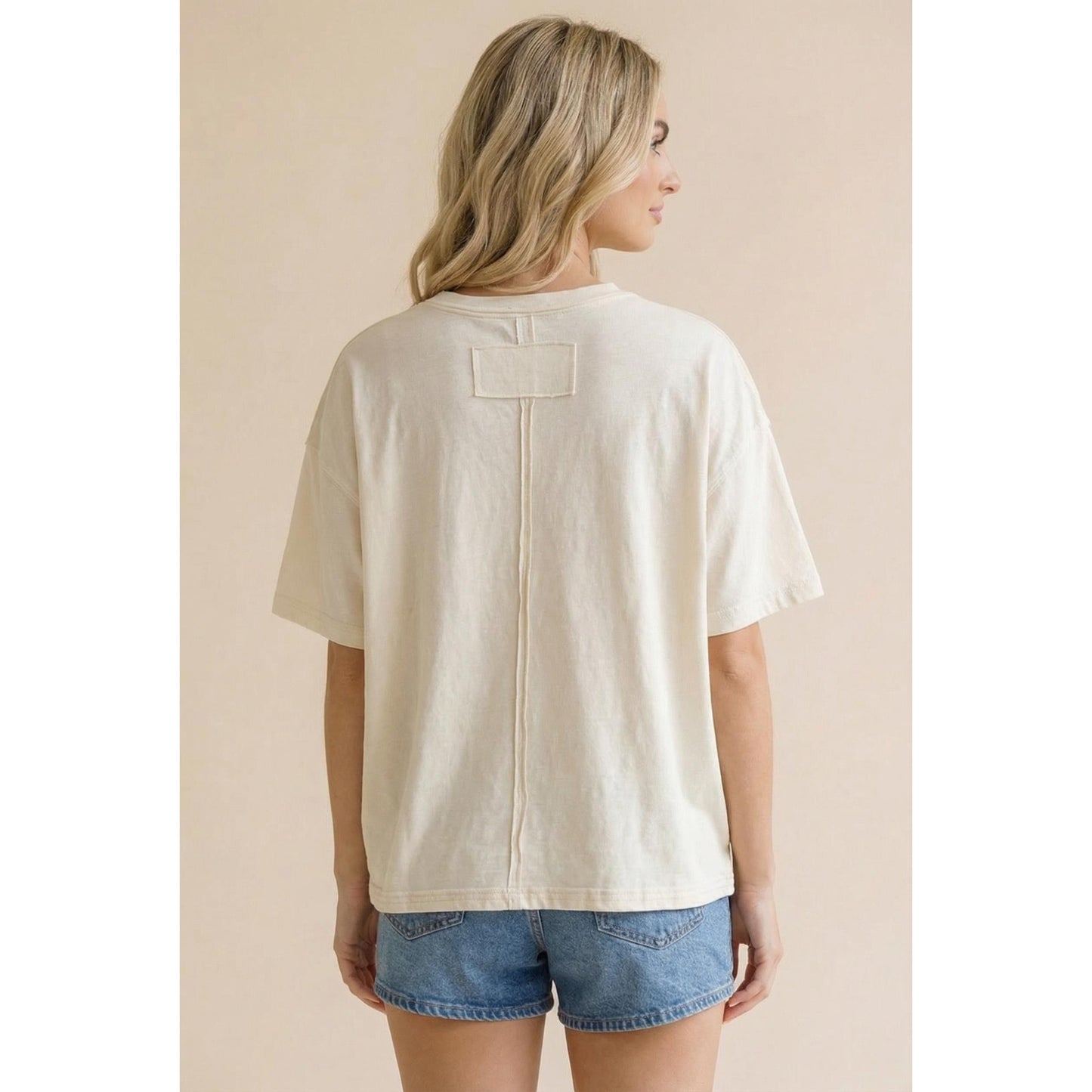 Woman wearing a beige t-shirt with a zipper on a beige background
