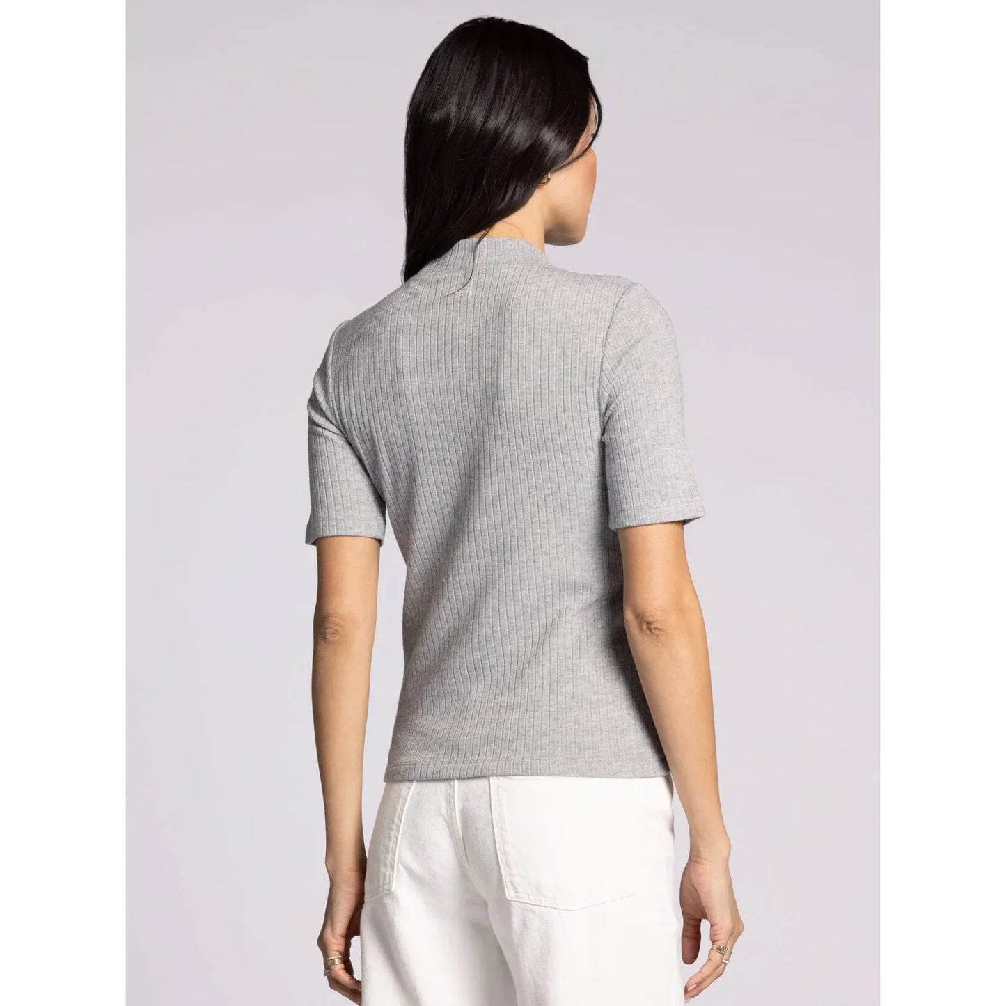 Person wearing a gray short-sleeve shirt and white pants on a light gray background