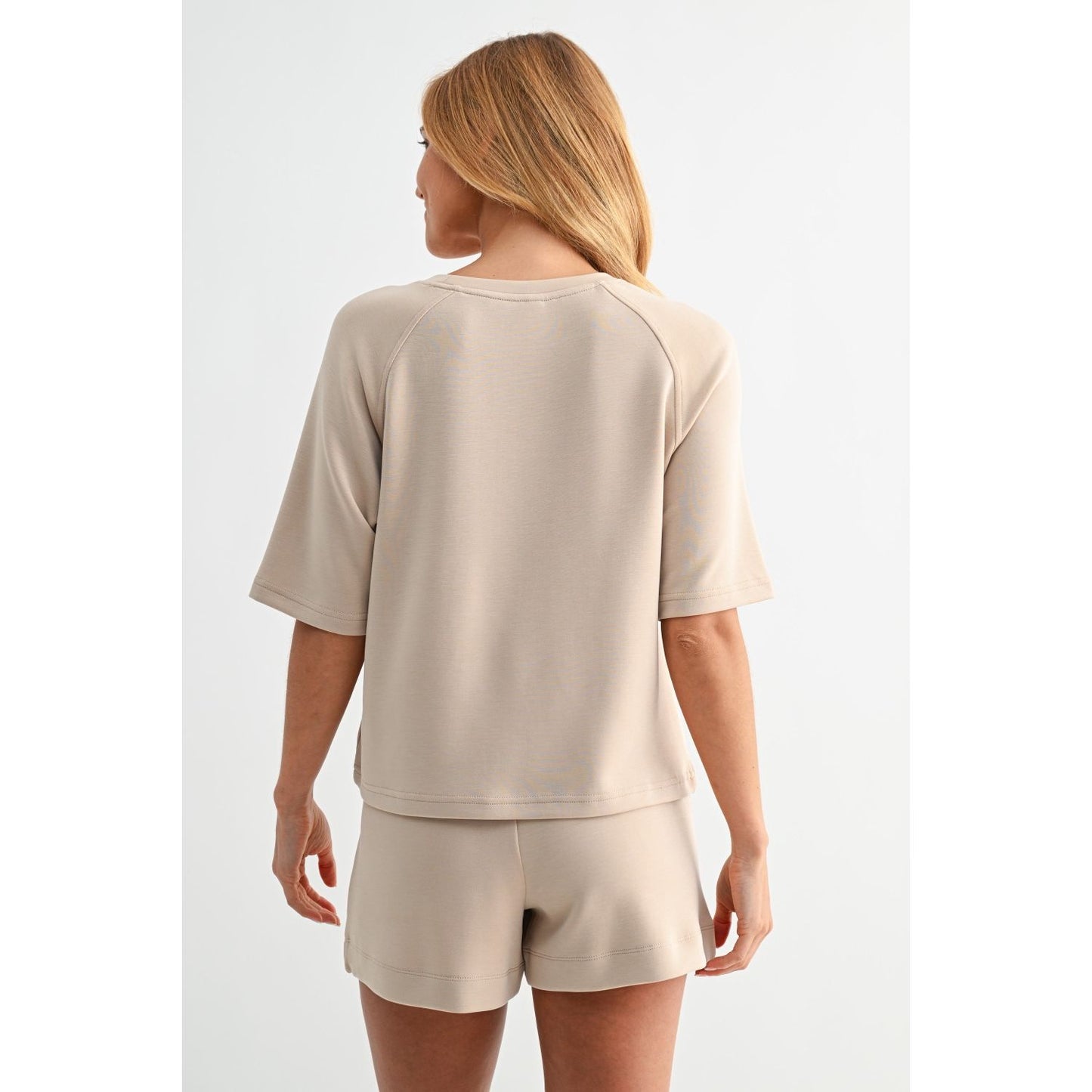 Woman wearing a beige lounge set on a white background