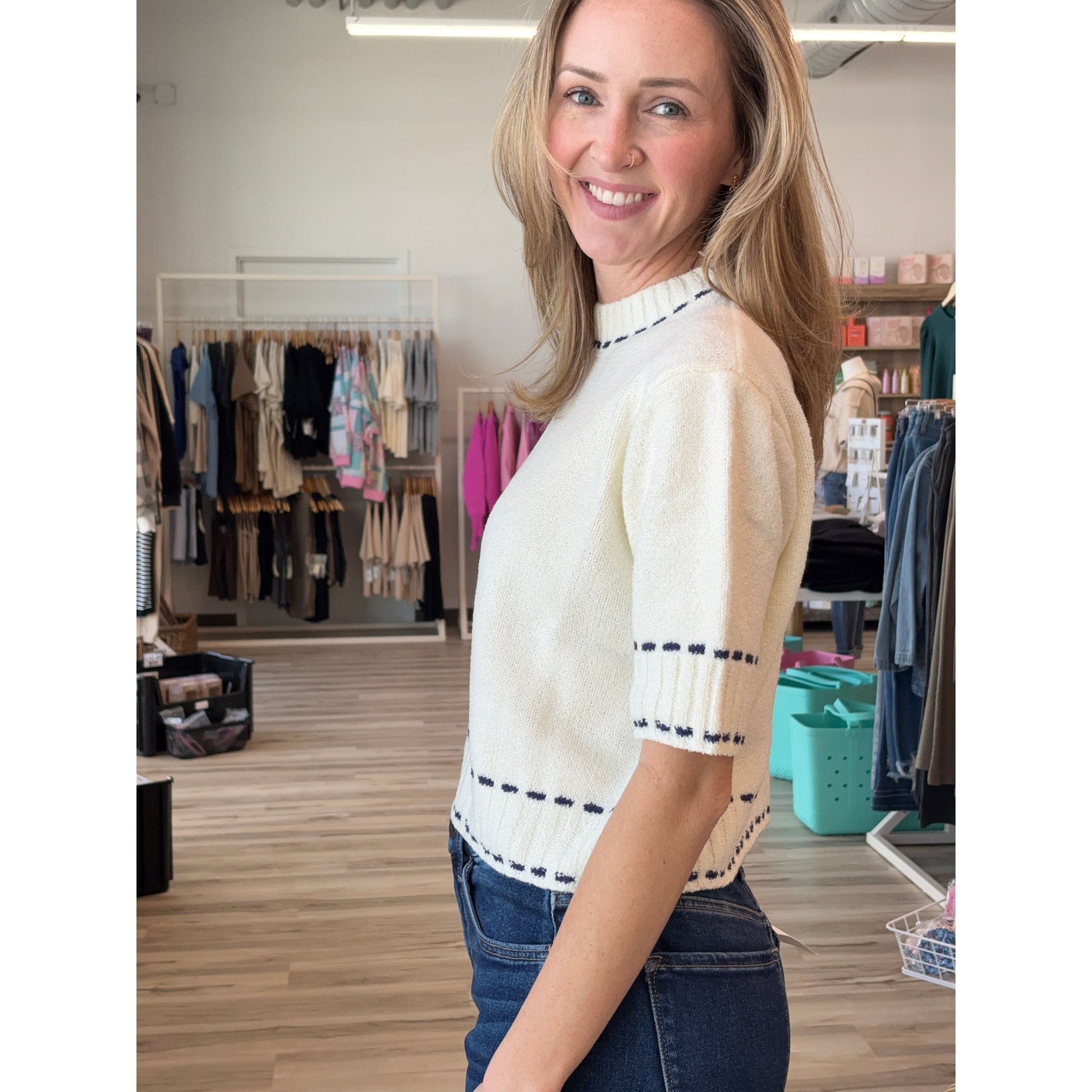 Side view of woman wearing cream knit short-sleeved sweater with navy detailing