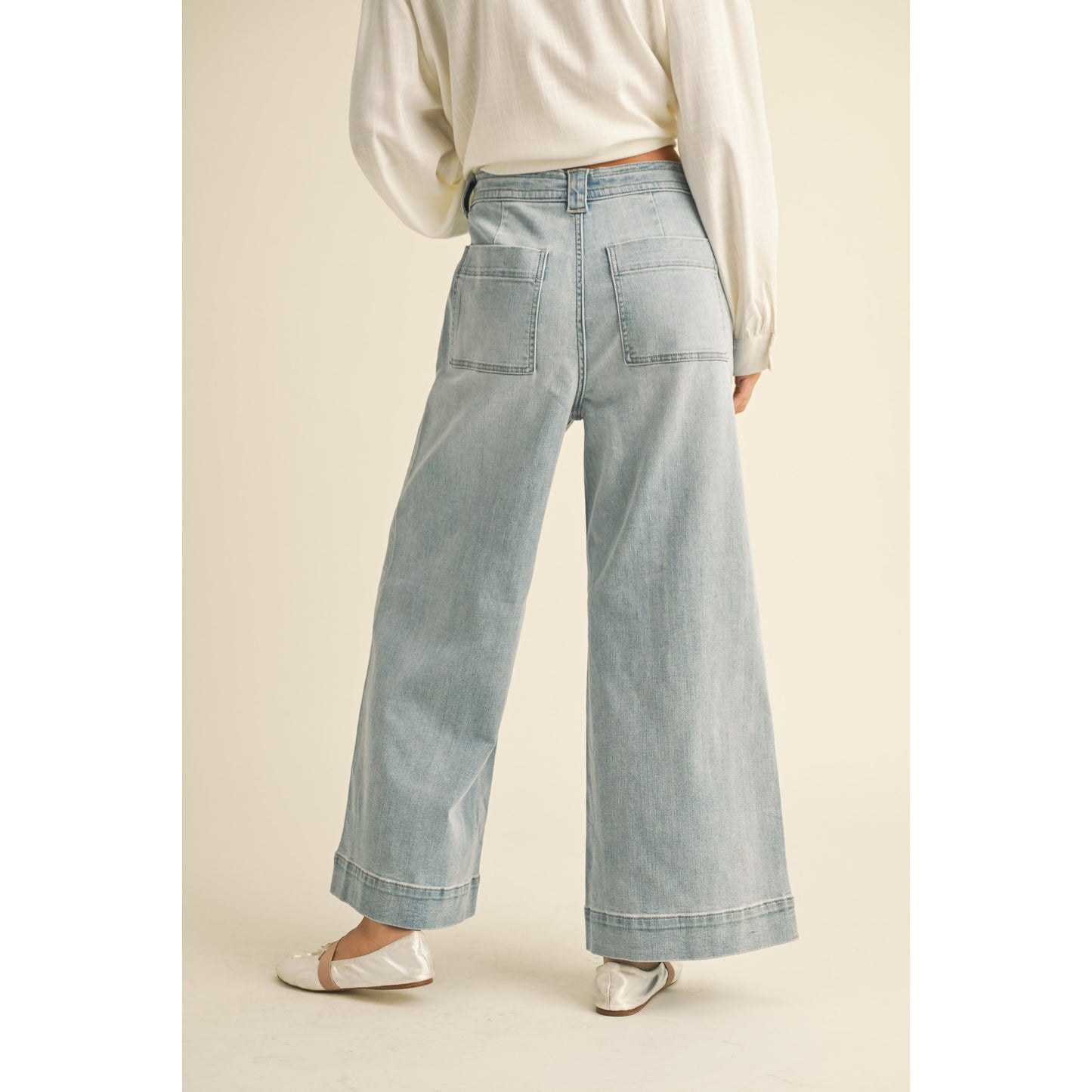 Light blue jeans worn by a person on a beige background