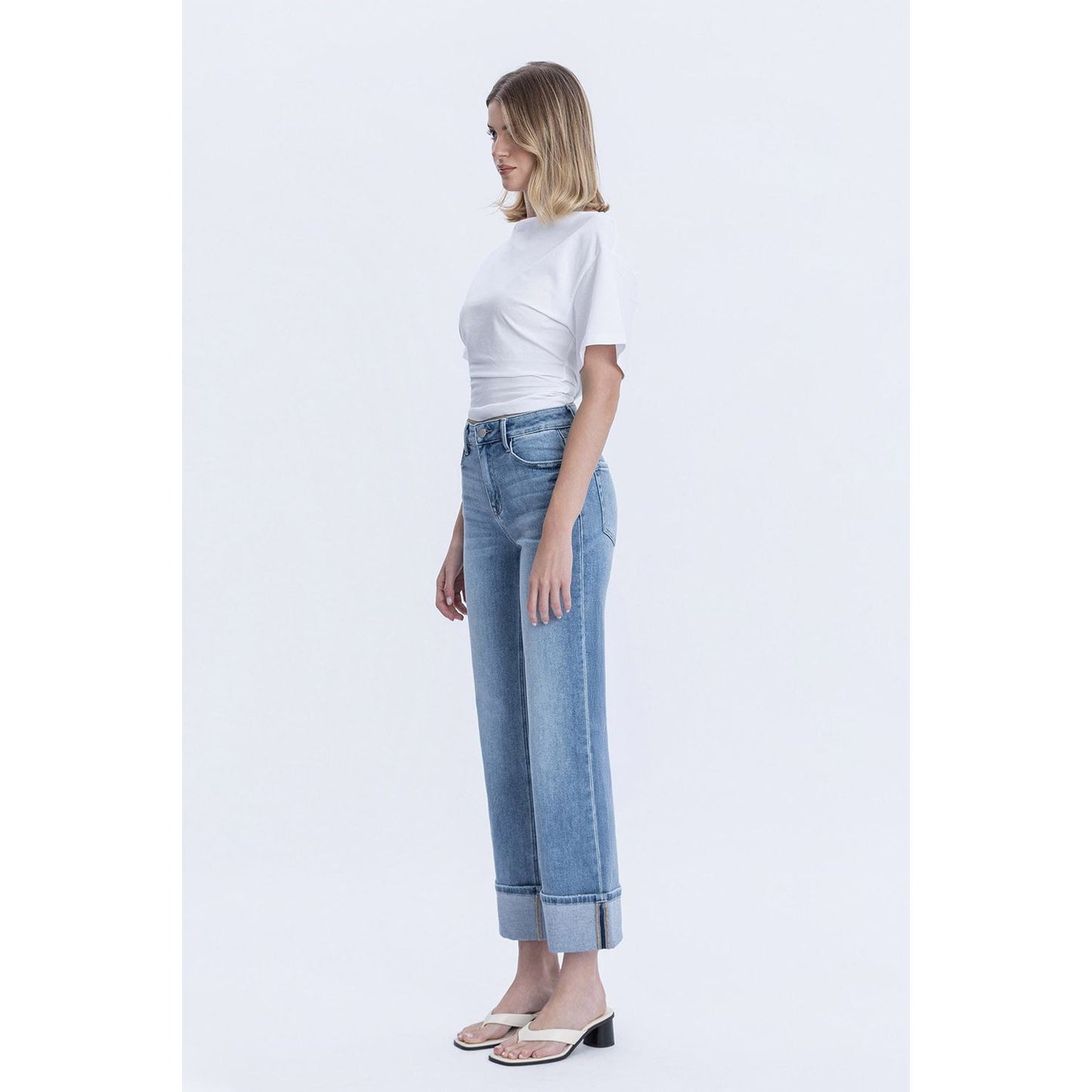 Person wearing blue jeans with cuffed bottoms and a black top in a store setting