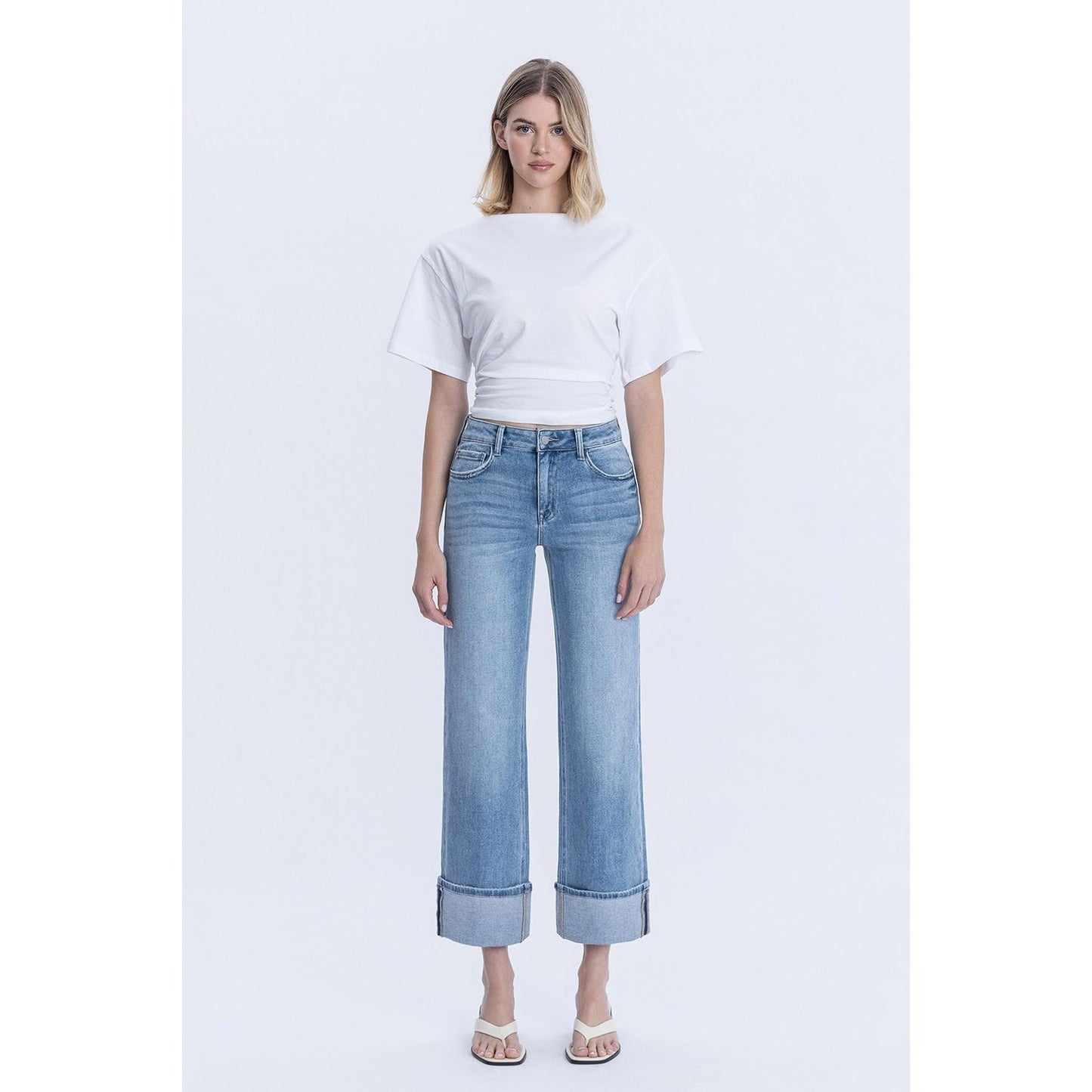 Person wearing blue jeans with cuffed bottoms and a black top in a store setting