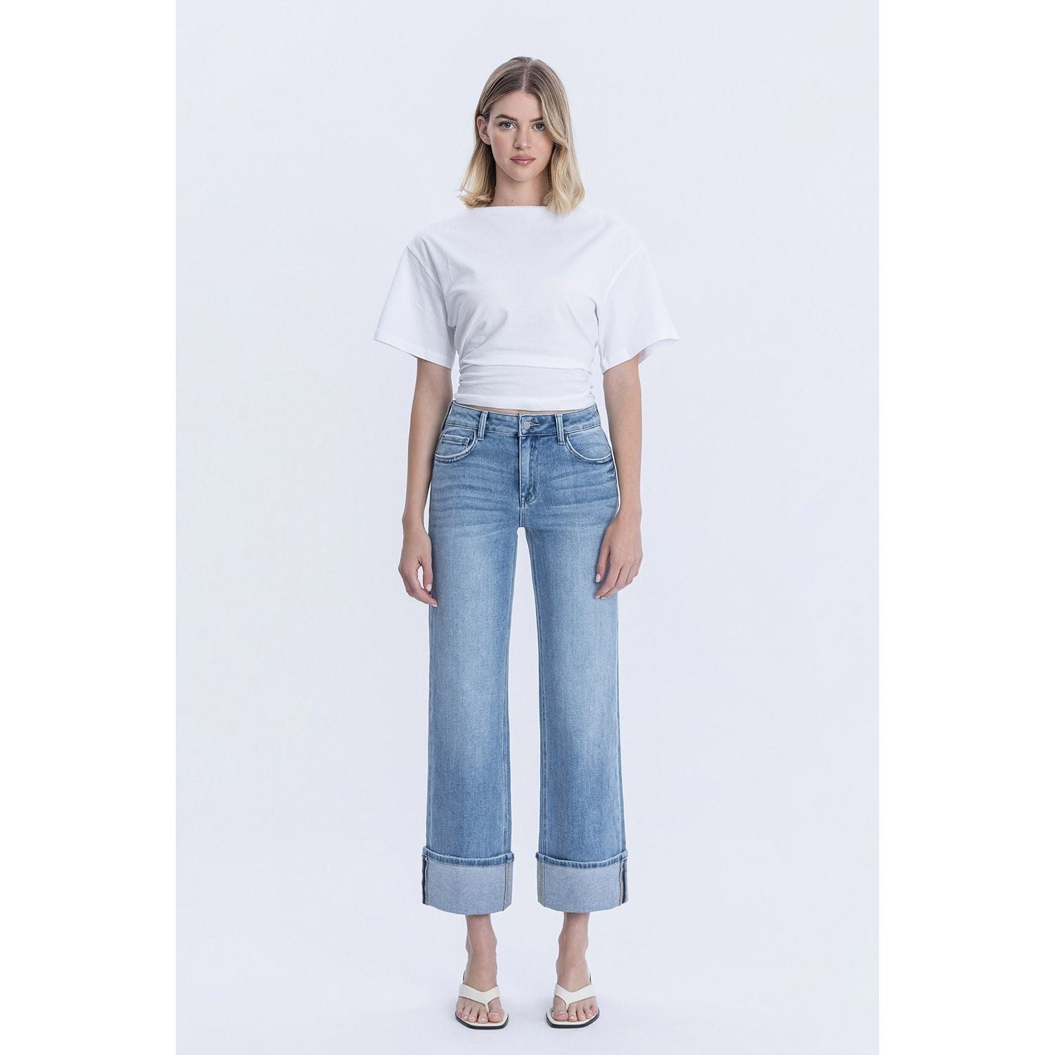 Person wearing blue jeans with cuffed bottoms and a black top in a store setting