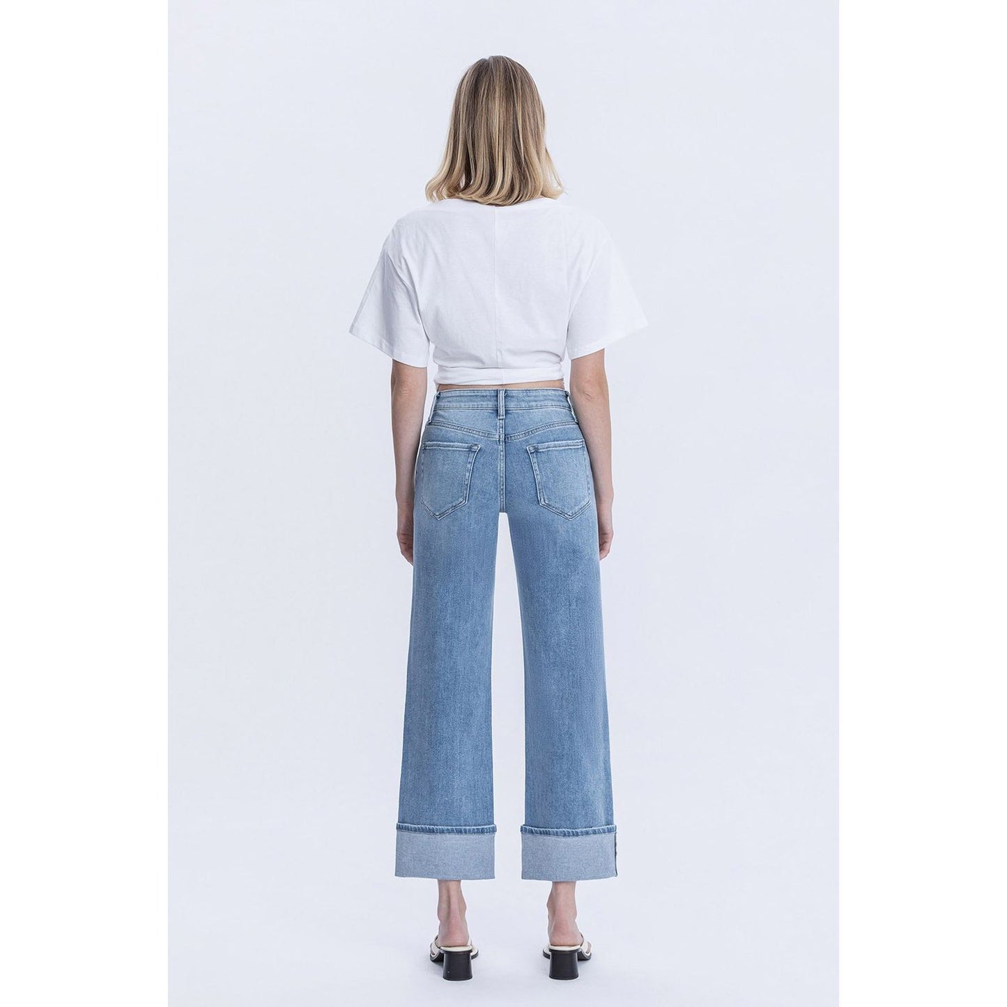 Person wearing blue jeans with cuffed bottoms and a black top in a store setting