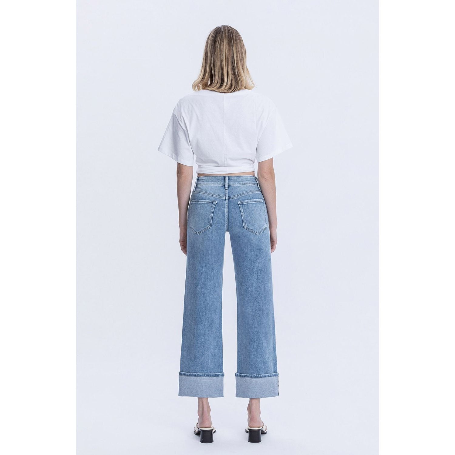 Person wearing blue jeans with cuffed bottoms and a black top in a store setting