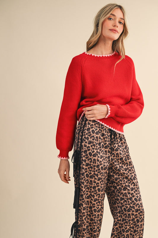Woman wearing a red sweater and leopard print pants on a beige background