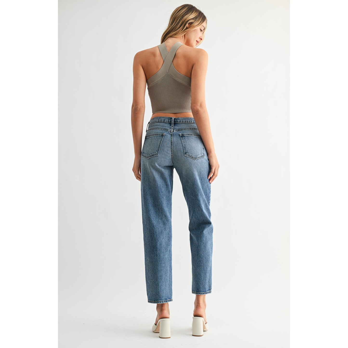 Woman wearing a green crop top and blue jeans on a white background