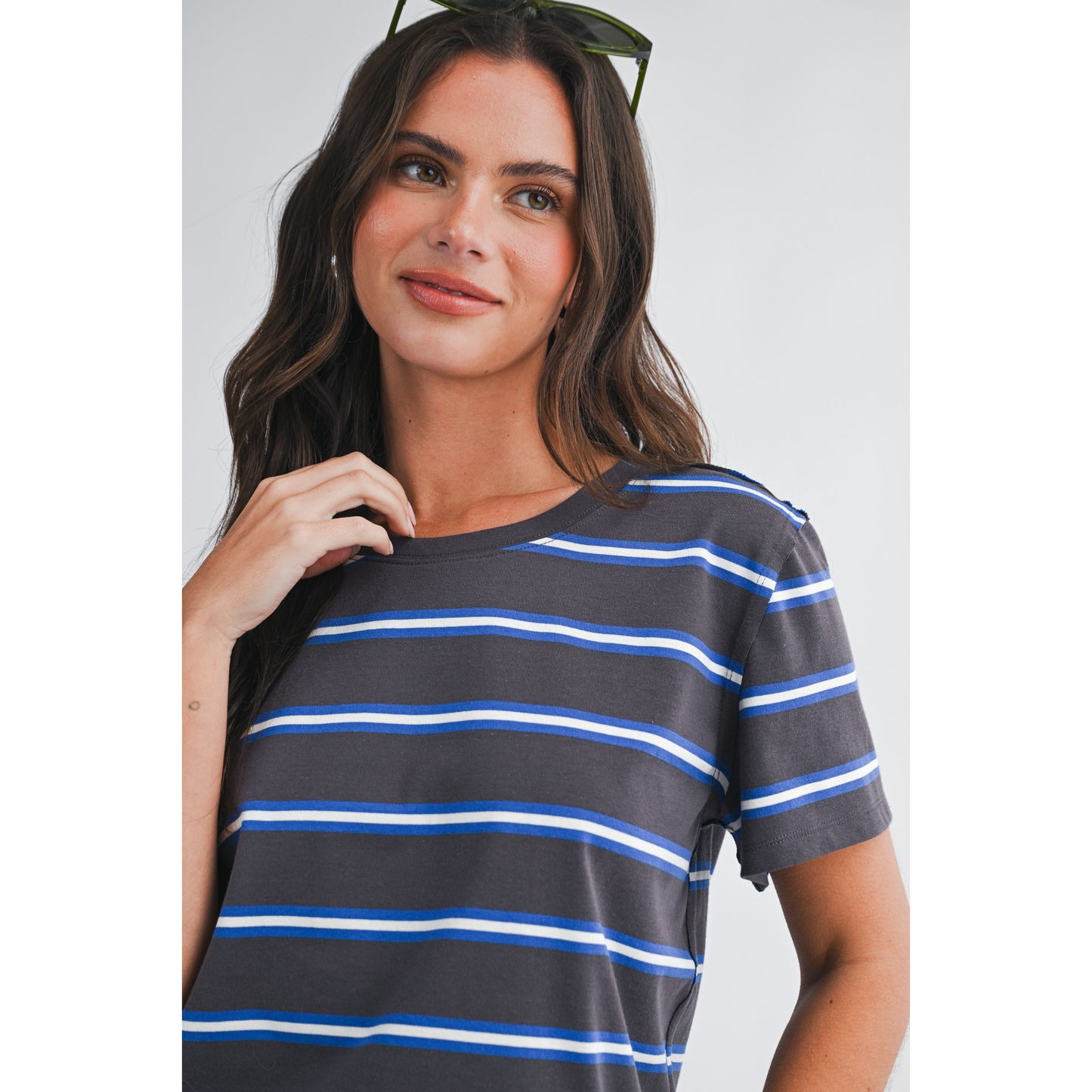 Woman wearing a gray and blue striped shirt against a plain background