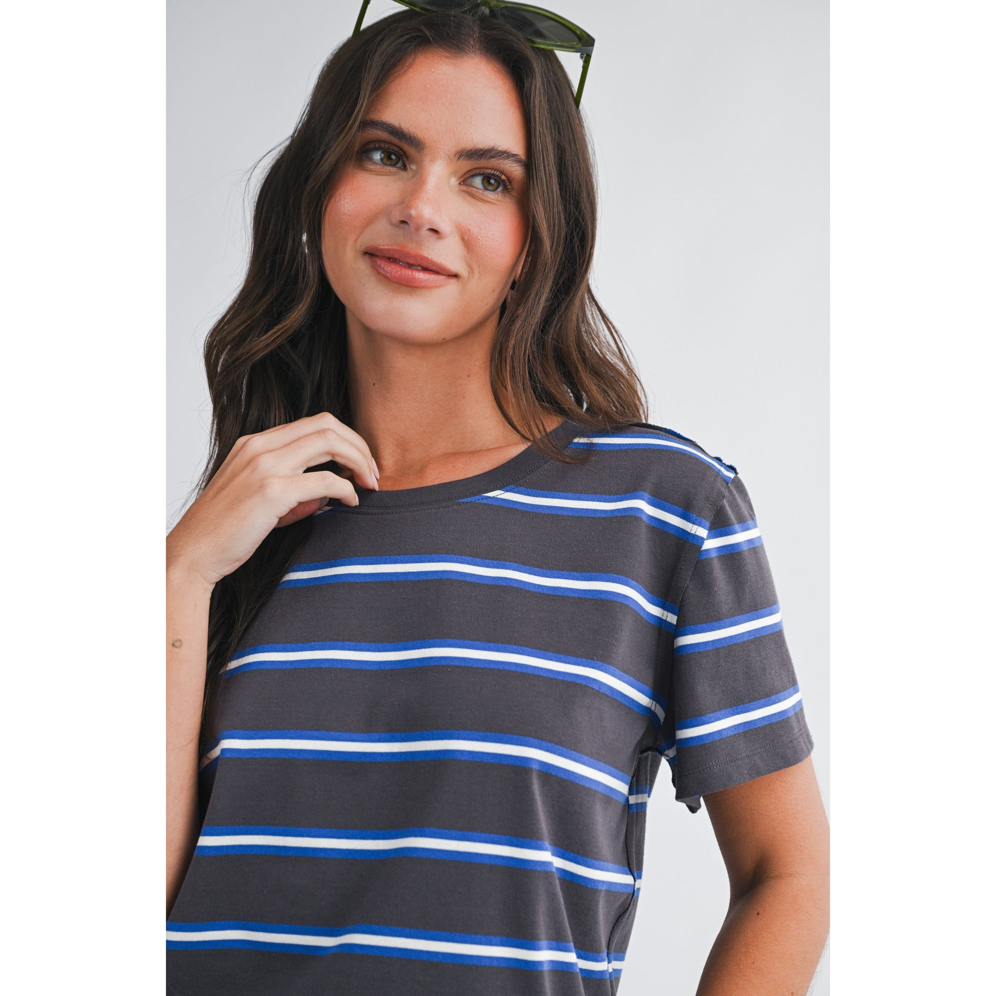 Woman wearing a gray and blue striped shirt against a plain background