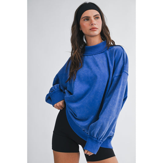 Woman wearing a blue oversized sweater and black shorts on a white background