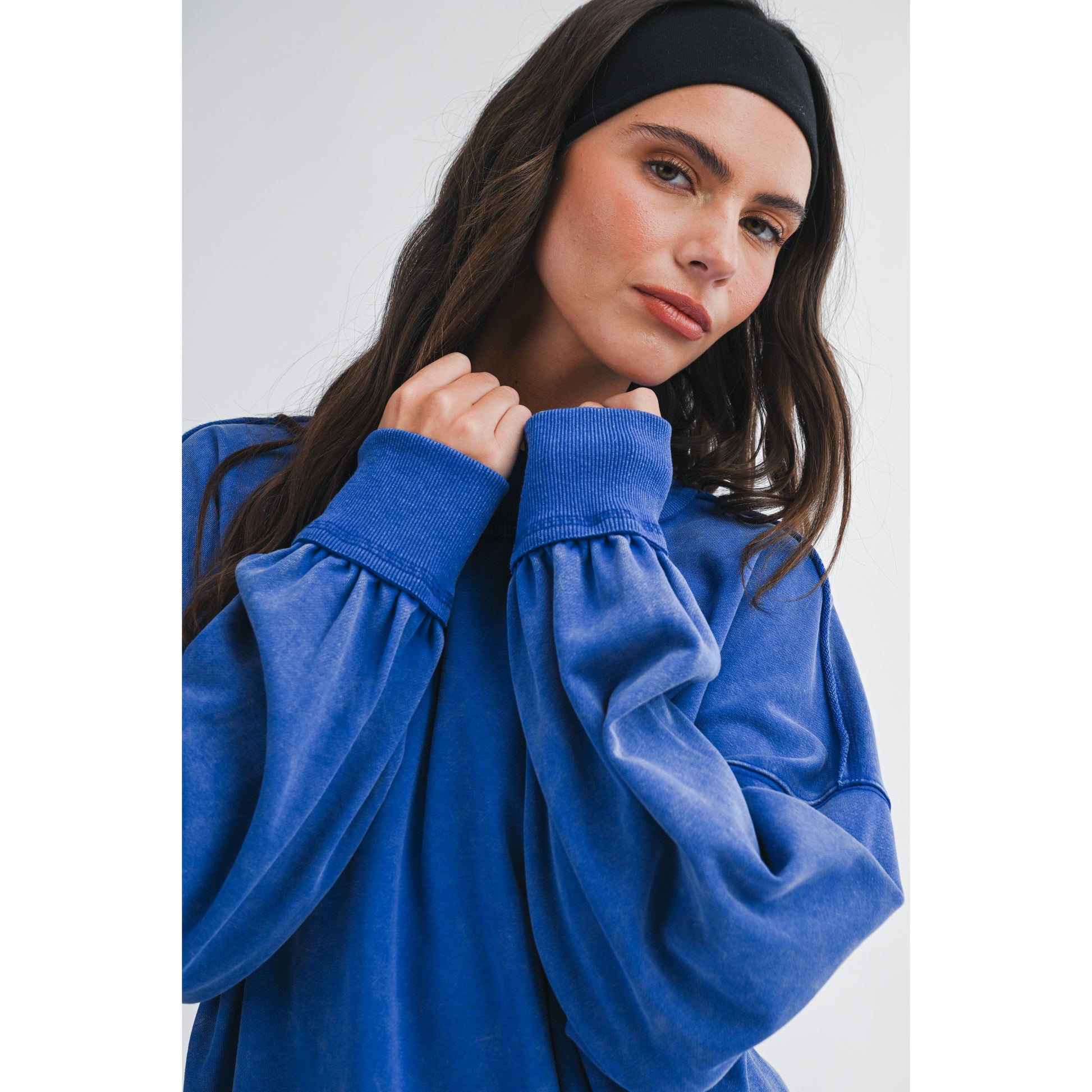 Woman wearing a blue oversized sweatshirt against a white background