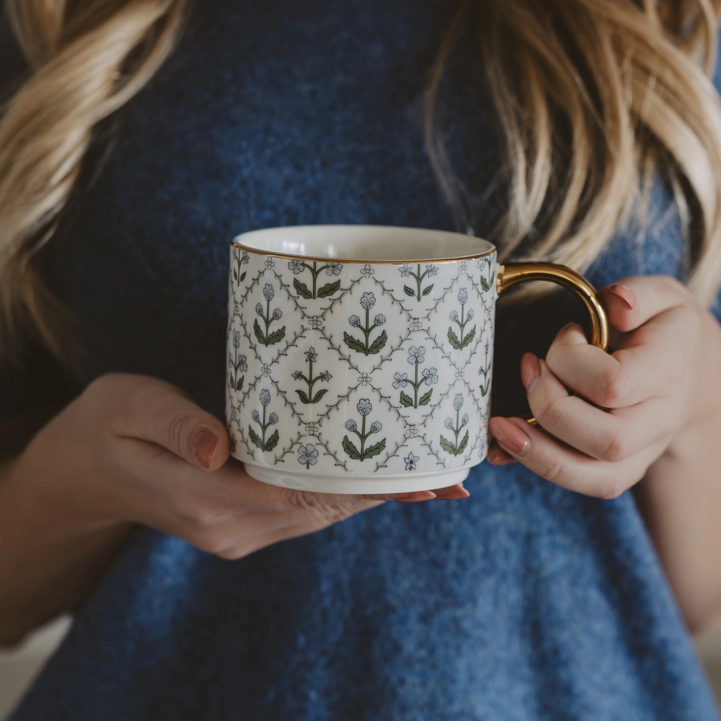 Person holding a patterned mug with a blue dress