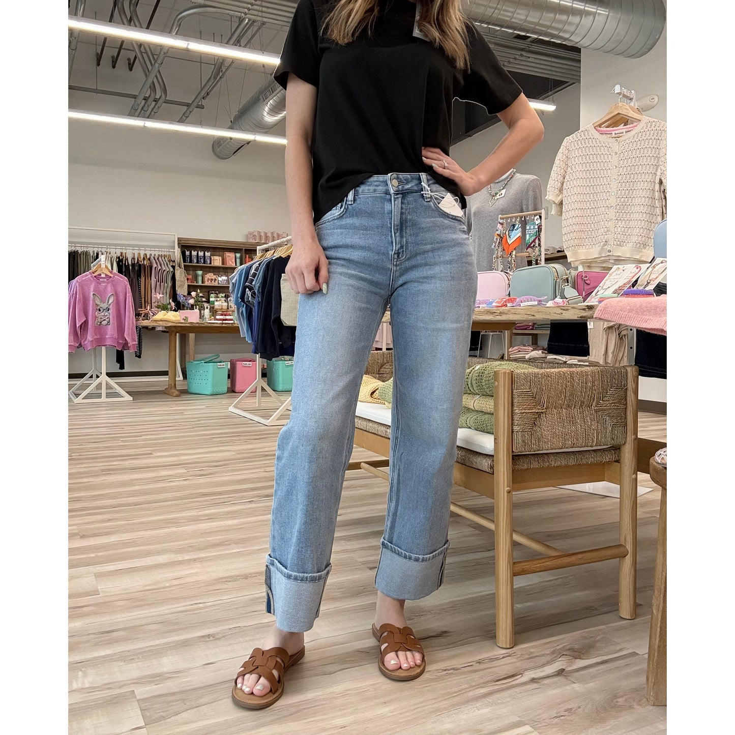 Person wearing blue jeans with cuffed bottoms and a black top in a store setting