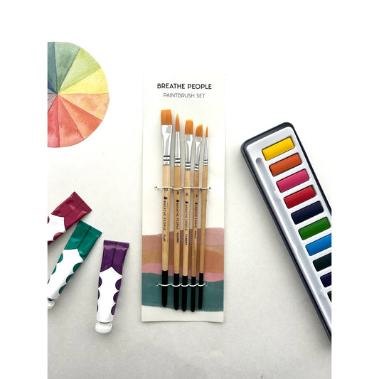 Set of paintbrushes with watercolor paints and color wheel on a light gray background
