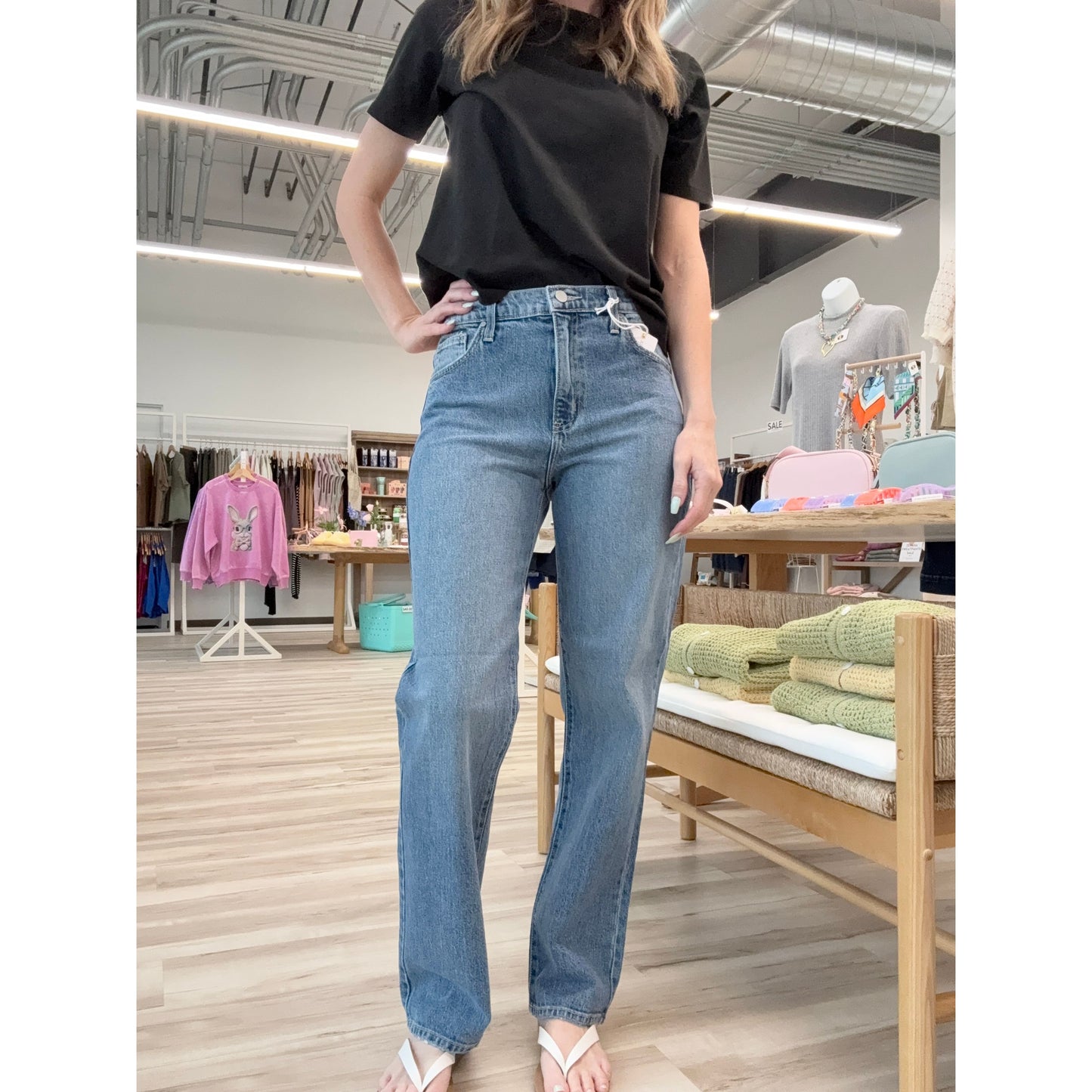 Person wearing a black t-shirt and blue jeans in a store setting