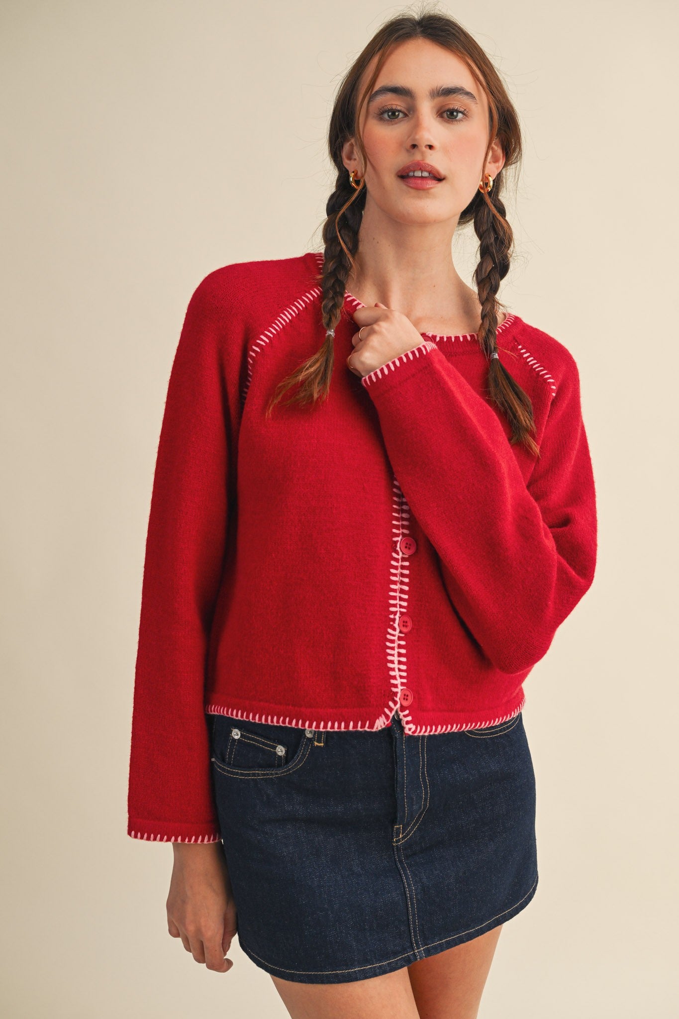 Woman wearing a red sweater with white trim on a beige background