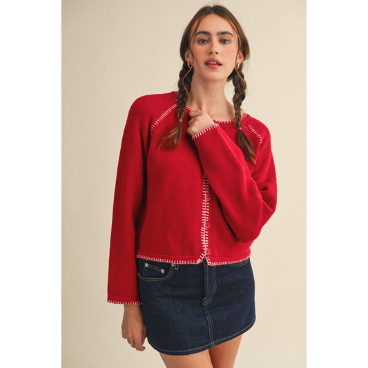 Woman wearing a red sweater with white trim on a beige background