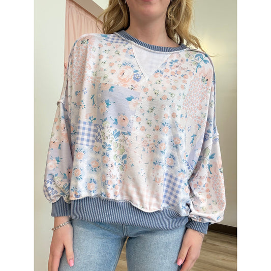Person wearing a floral and checkered blouse over a striped shirt.