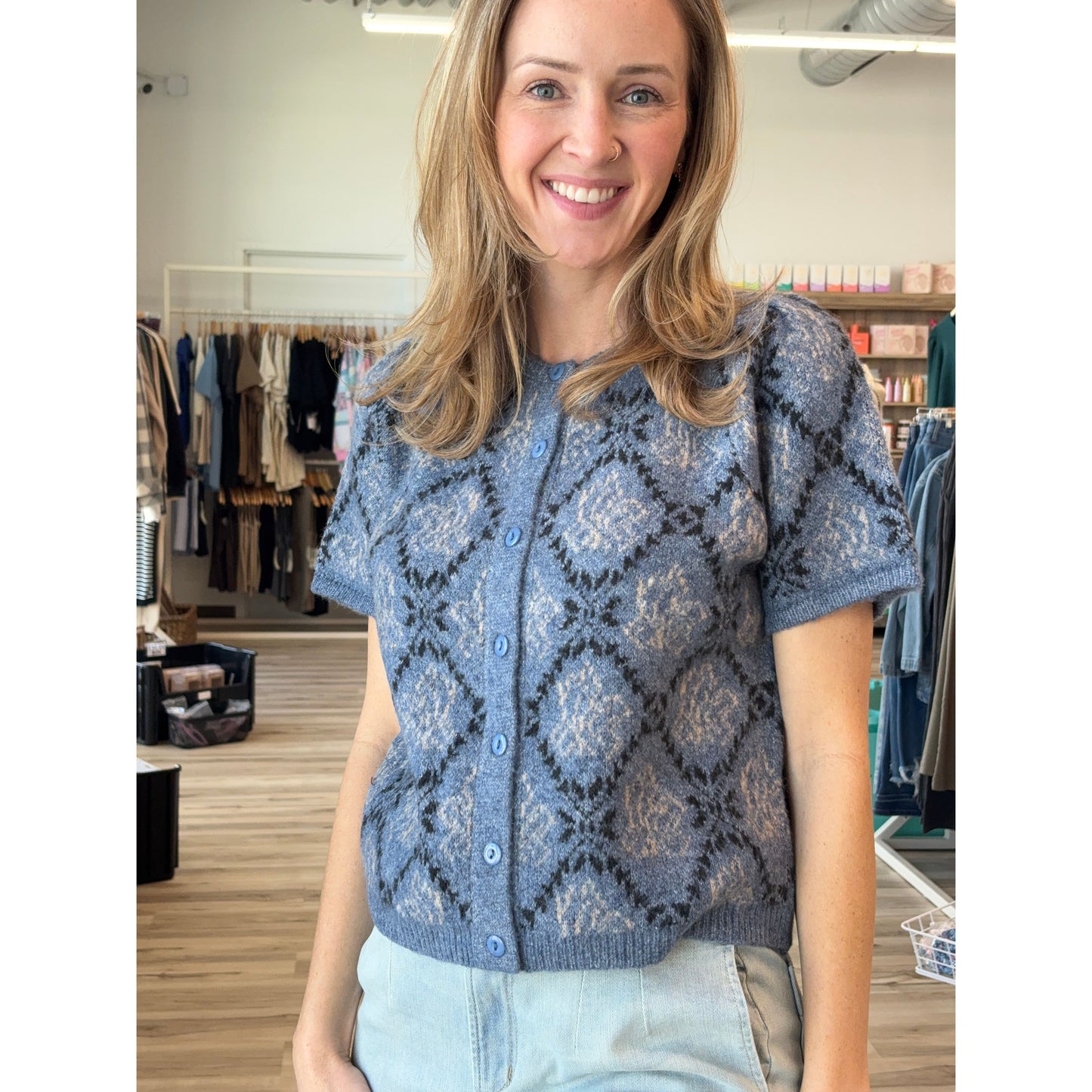 Woman wearing a blue patterned short-sleeved knit cardigan in a store setting