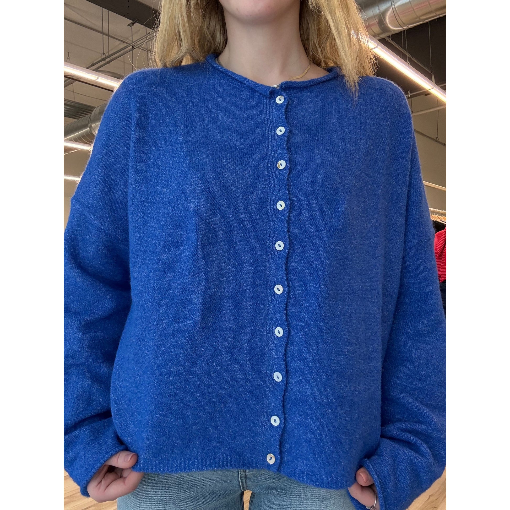 Close-up of a blue garment with button details, held by a person.