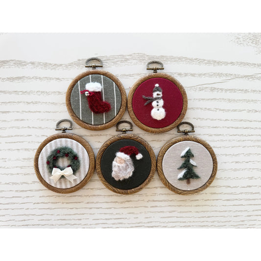 Set of five embroidered Christmas-themed mini hoops on a white wooden surface