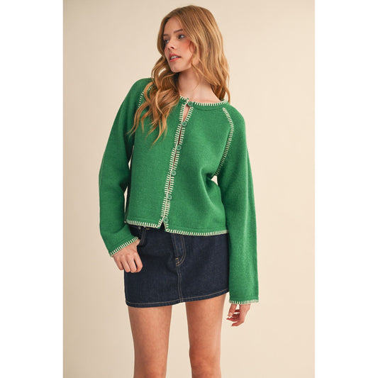 Woman wearing a green sweater with white trim on a beige background