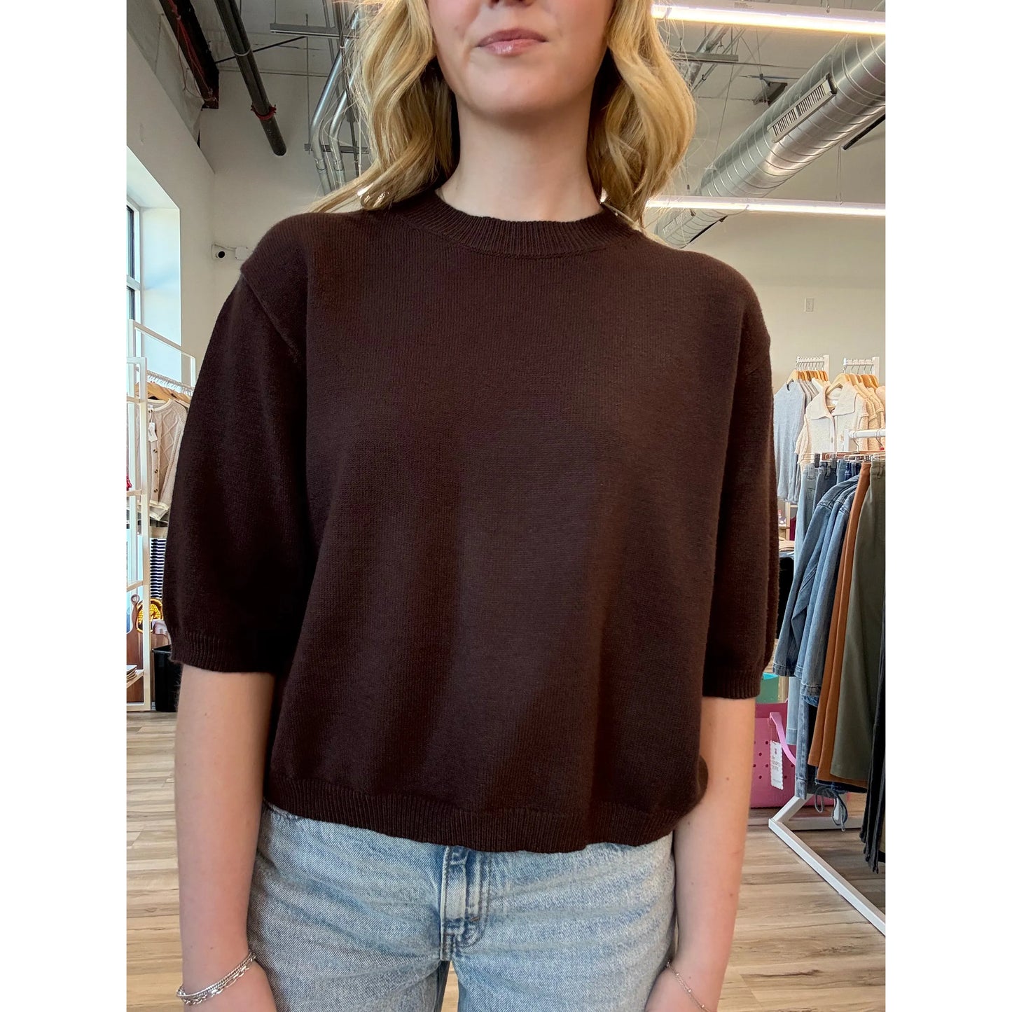 Close-up of a person wearing a brown short-sleeve knit sweater