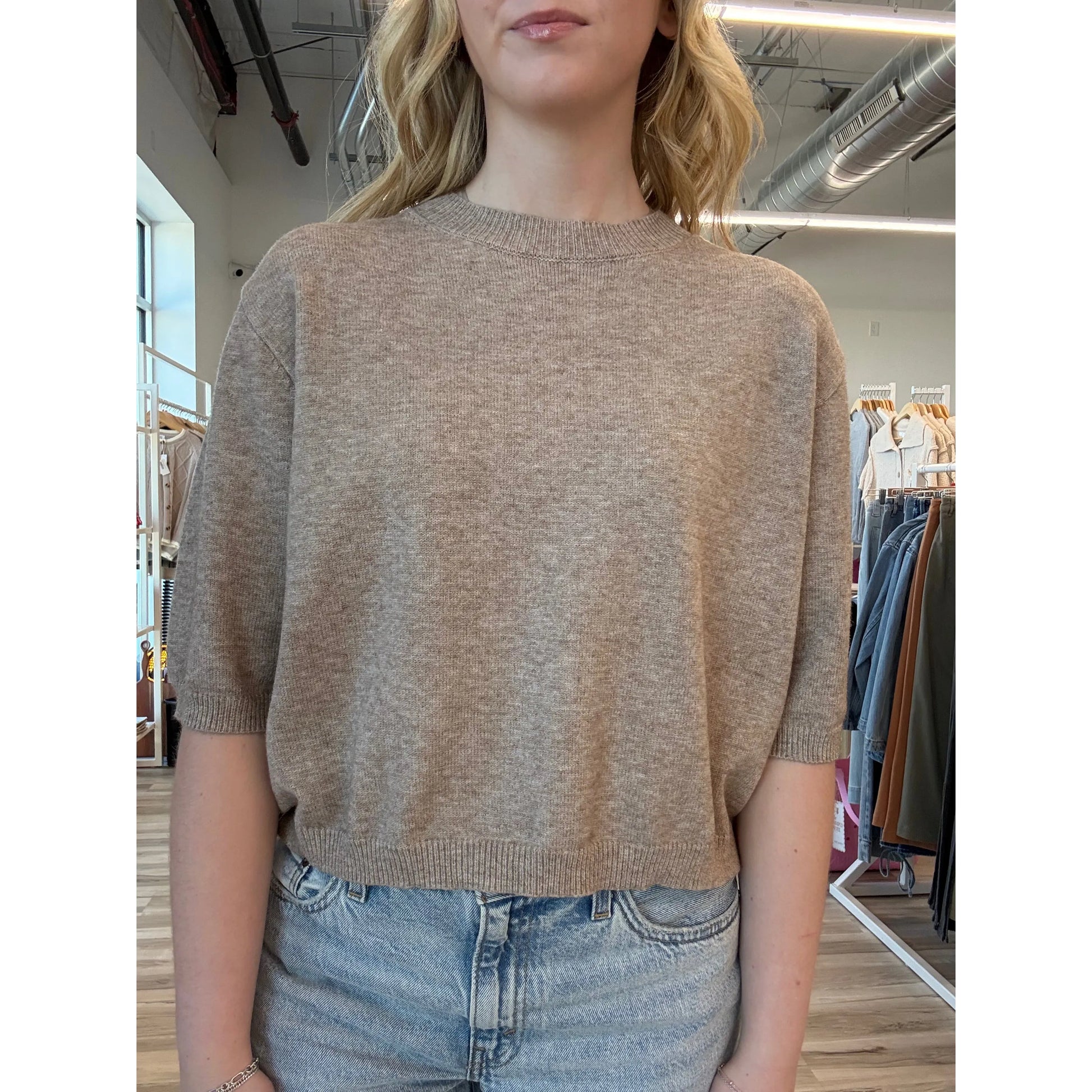 Close up of person wearing a beige short-sleeve knit sweater