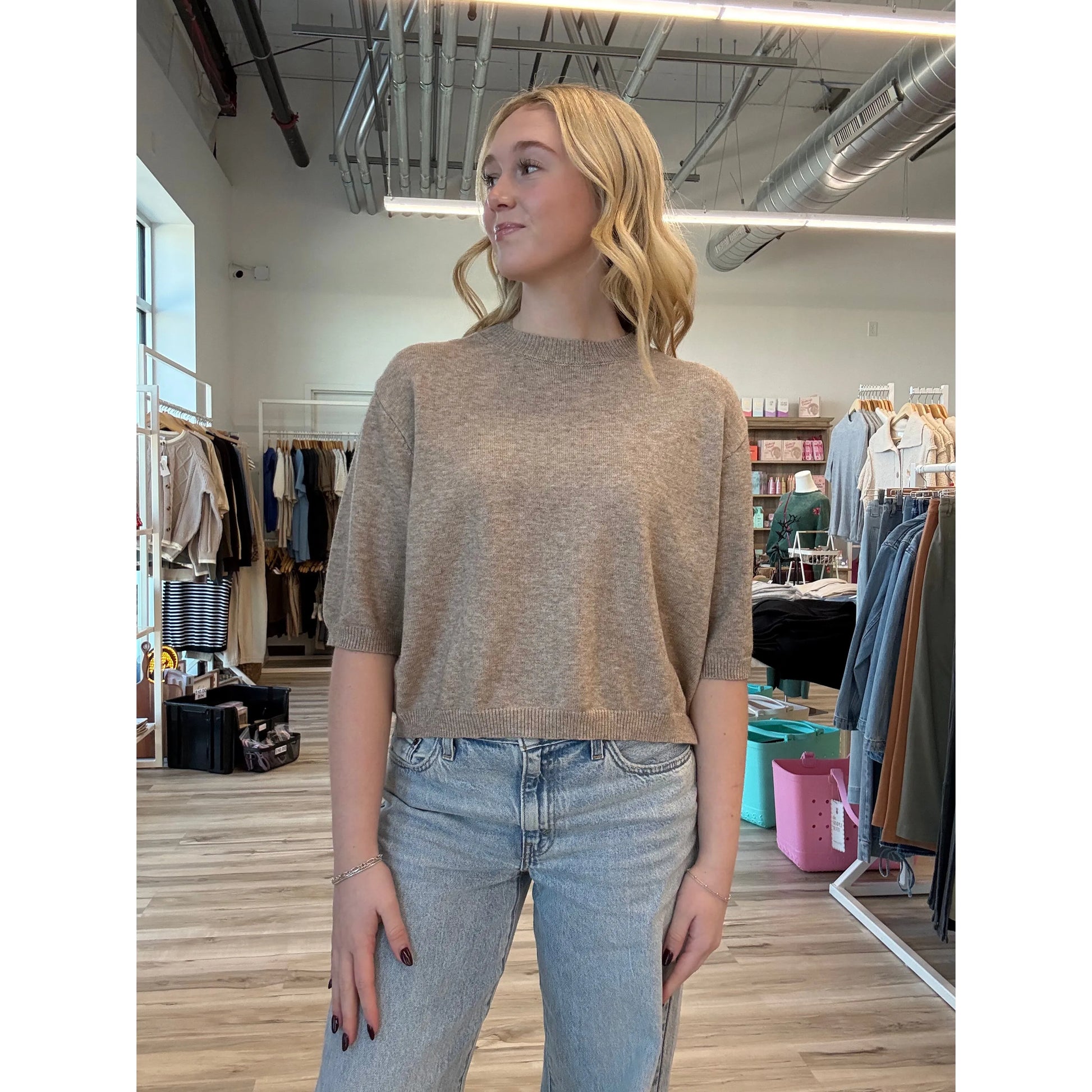 Woman wearing a short-sleeve beige knit top with a relaxed fit