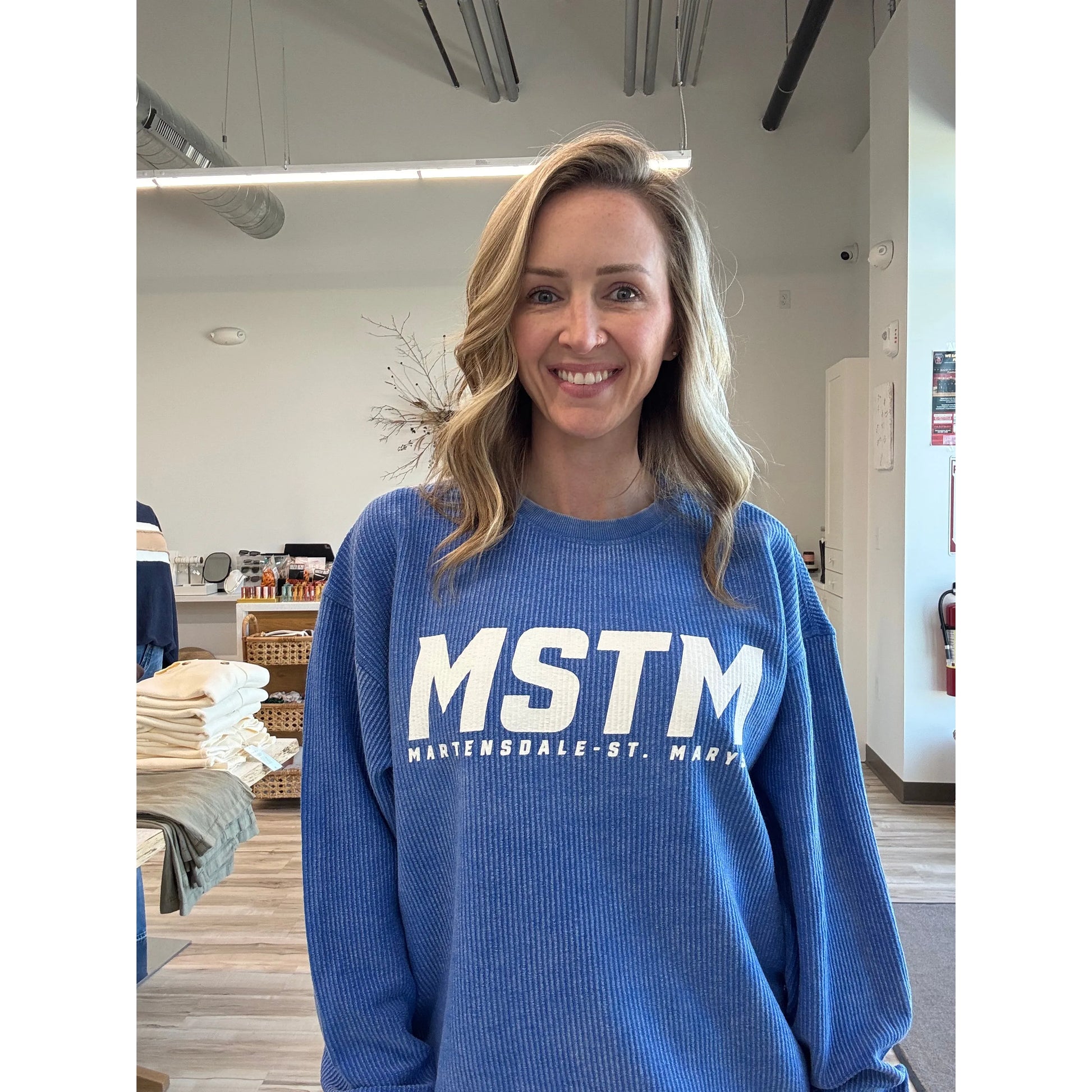 Person wearing a blue sweater with 'MSTM' text in a casual indoor setting