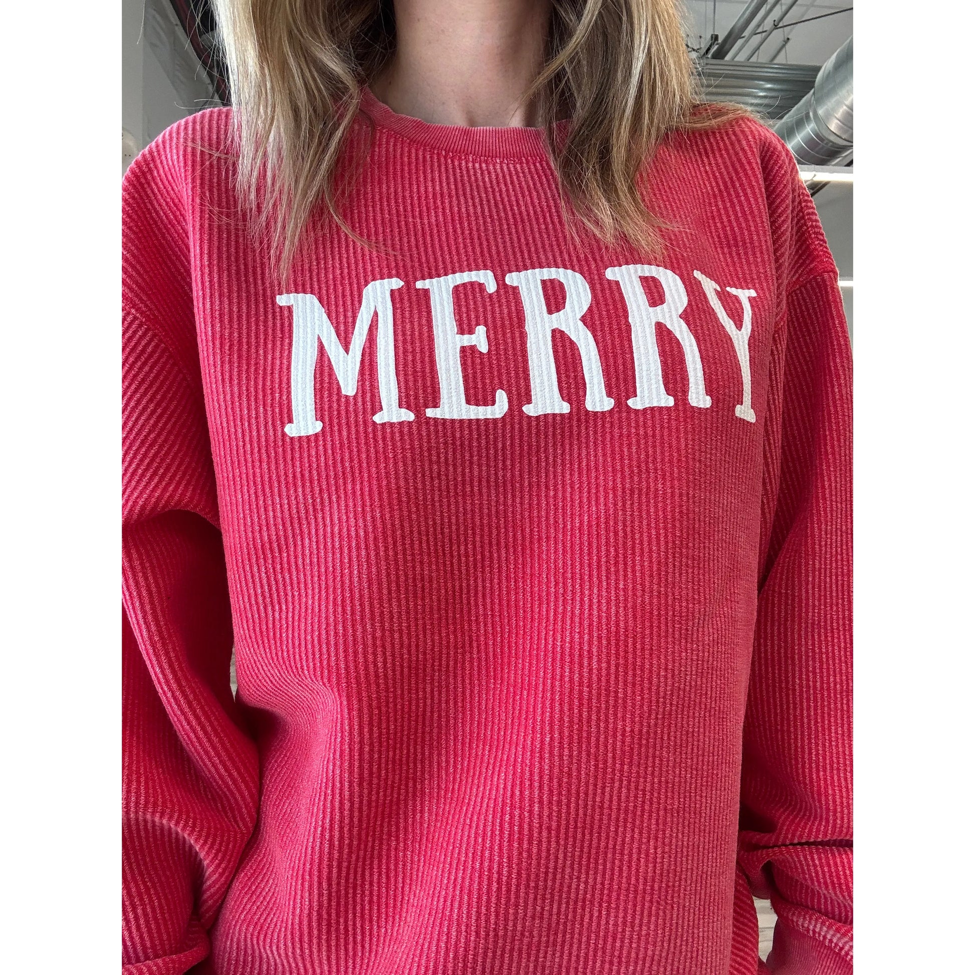 Red ribbed sweater with 'MERRY' text worn by a person.