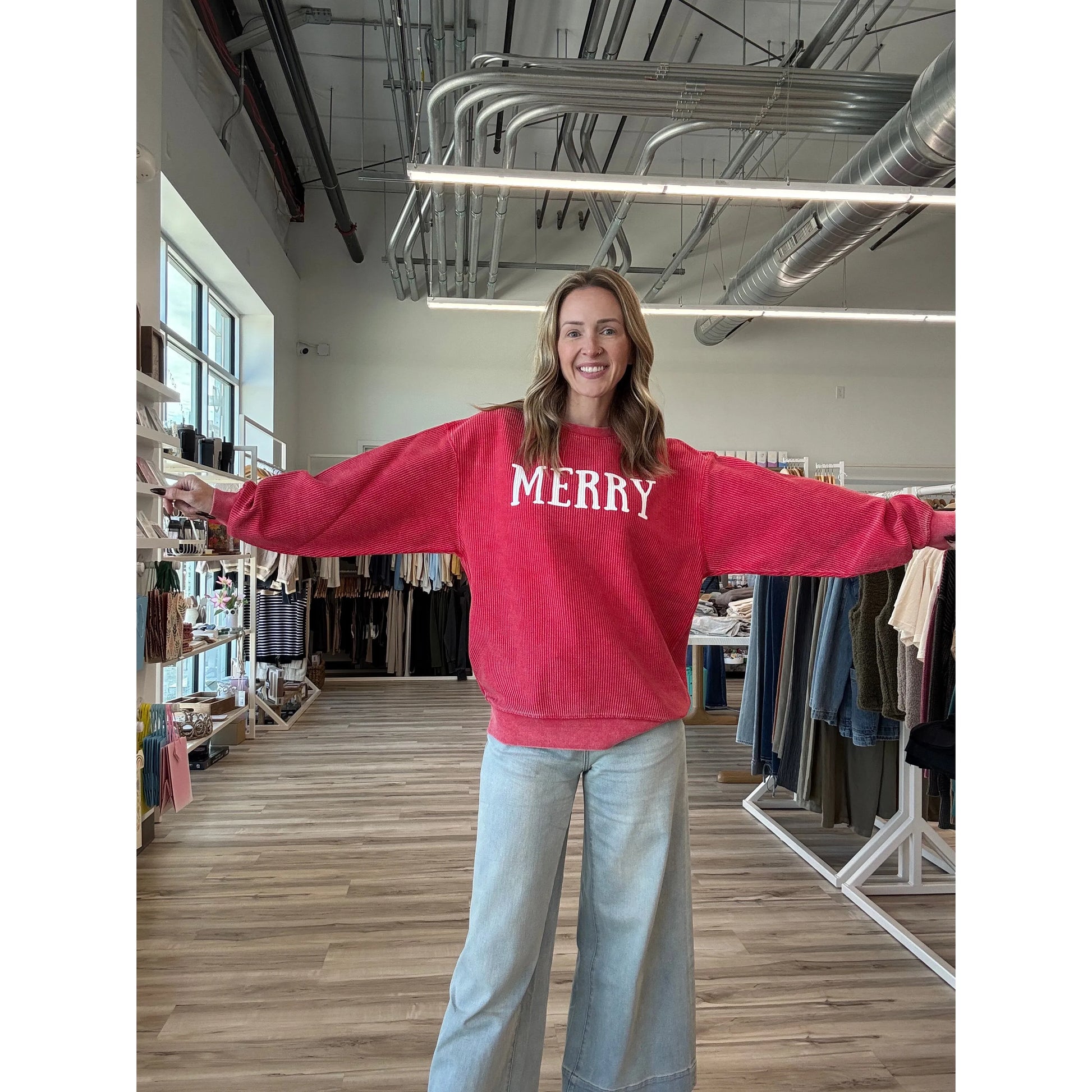Person wearing a red sweatshirt with 'MERRY' text in a store setting