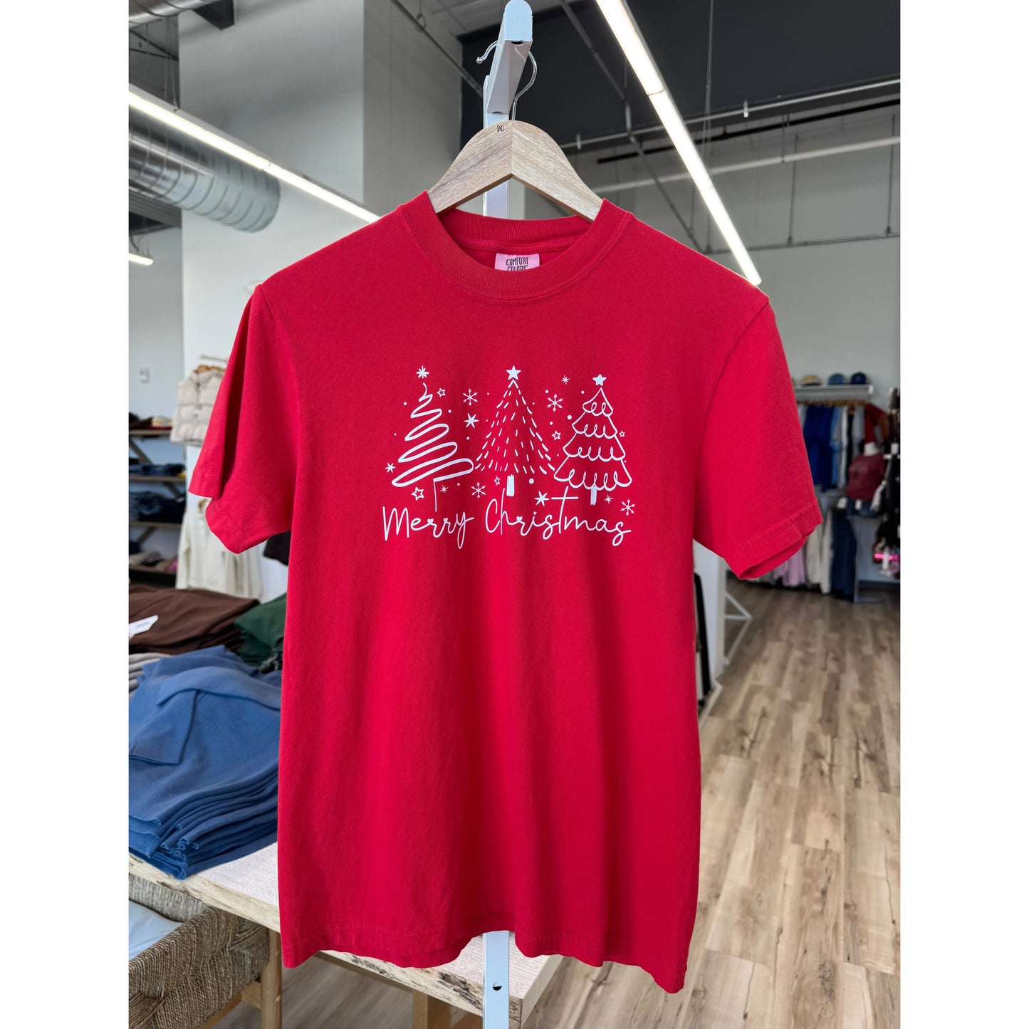 Red t-shirt with Christmas design on a hanger in a store.