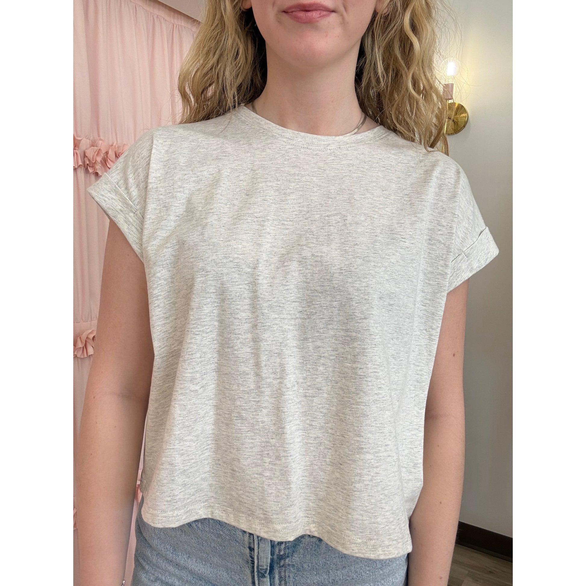 Person wearing a light-colored t-shirt with a neutral background