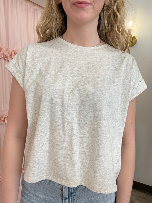 Person wearing a light-colored t-shirt with a neutral background