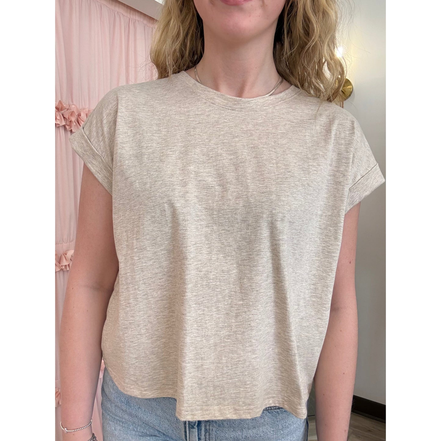 Person wearing a beige t-shirt with a neutral background