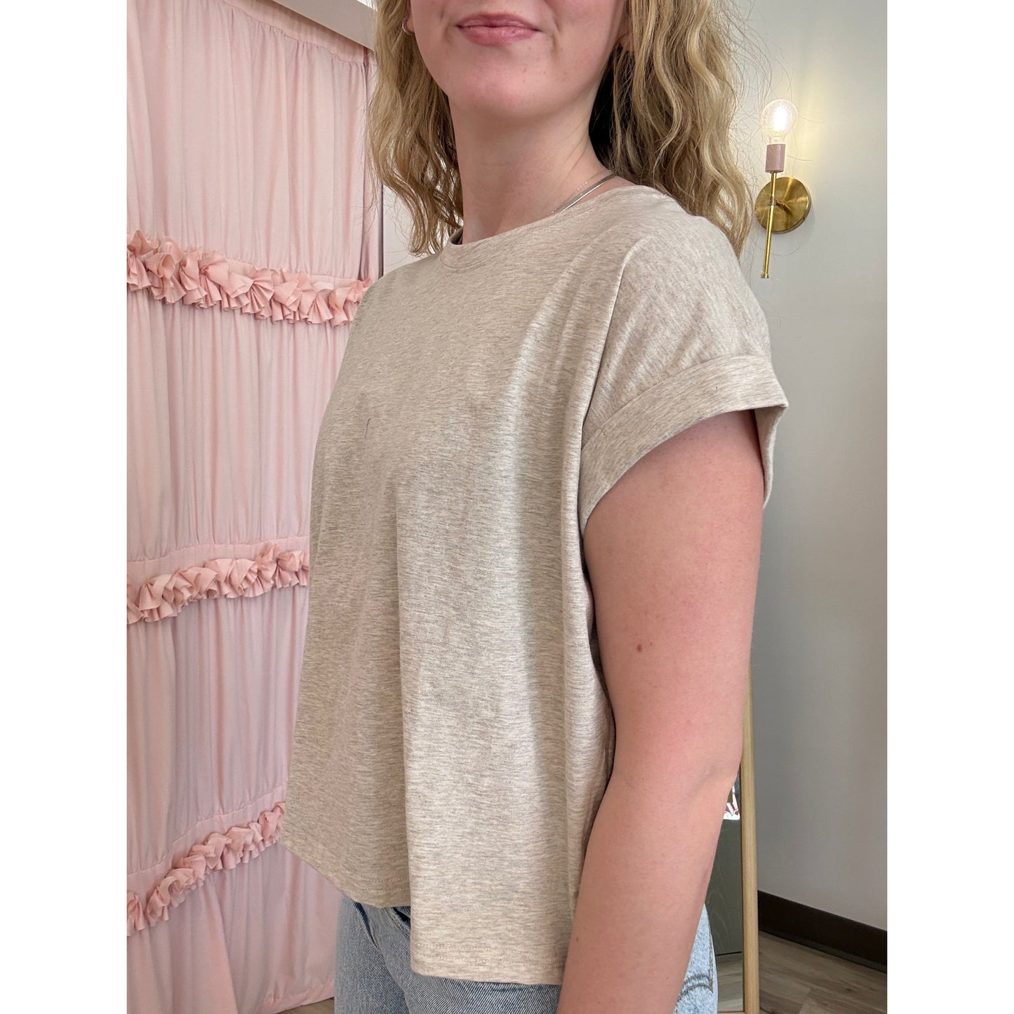 Woman wearing a beige t-shirt in a room with pink decorative elements.
