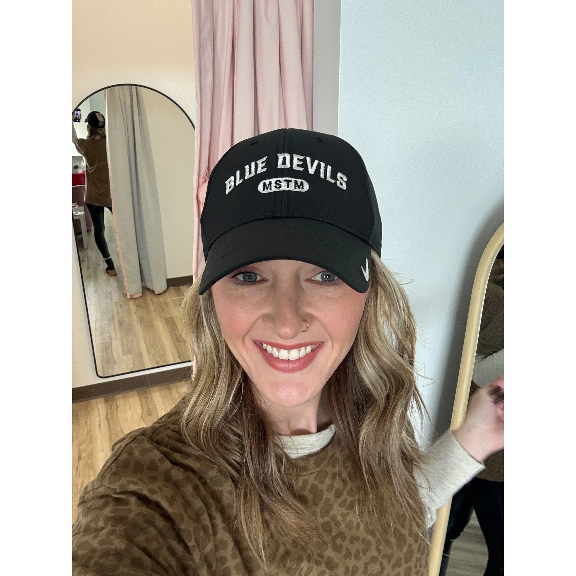 Person wearing a black cap with 'Blue Devils MSTM' text, standing in a store setting