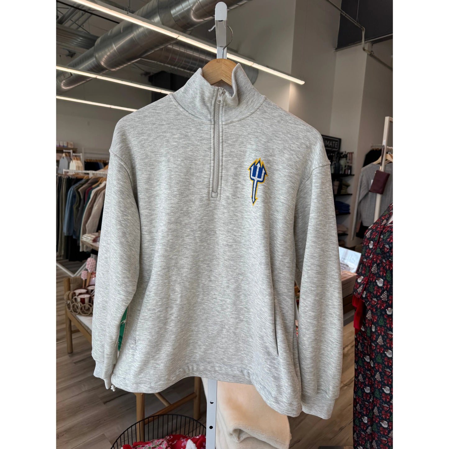 Gray pullover with a logo on a hanger in a store setting