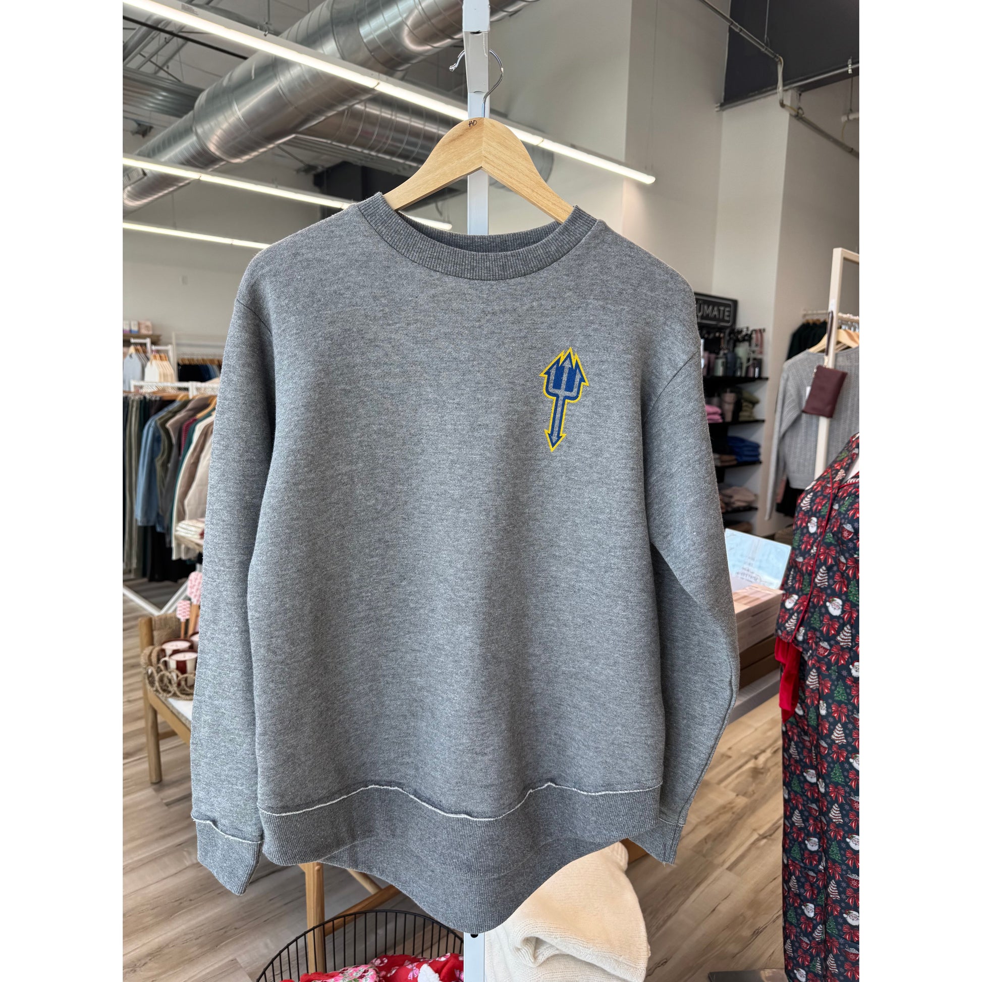 Gray sweatshirt with a logo on a hanger in a store setting