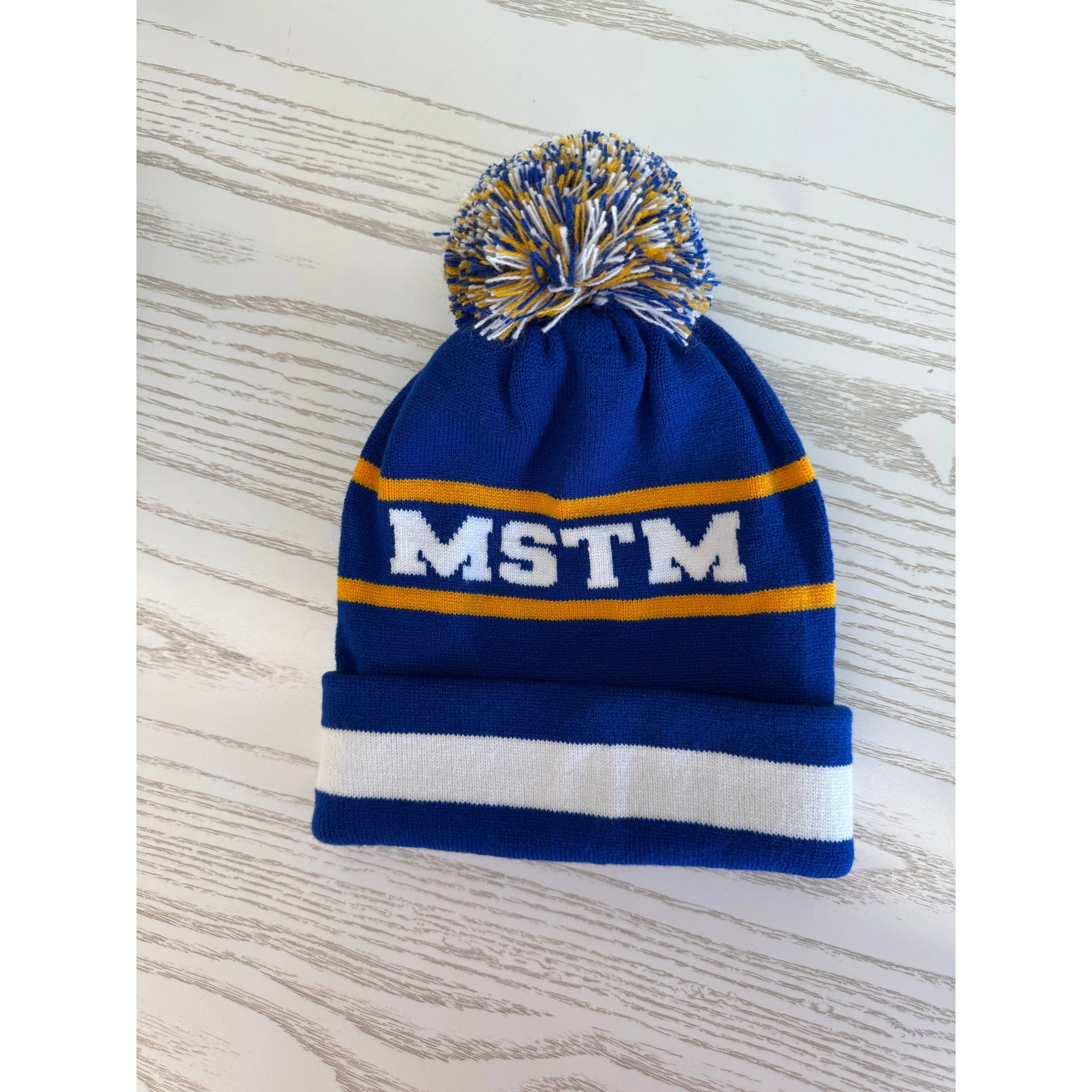Blue knit beanie with pom-pom and 'MSTM' branding
