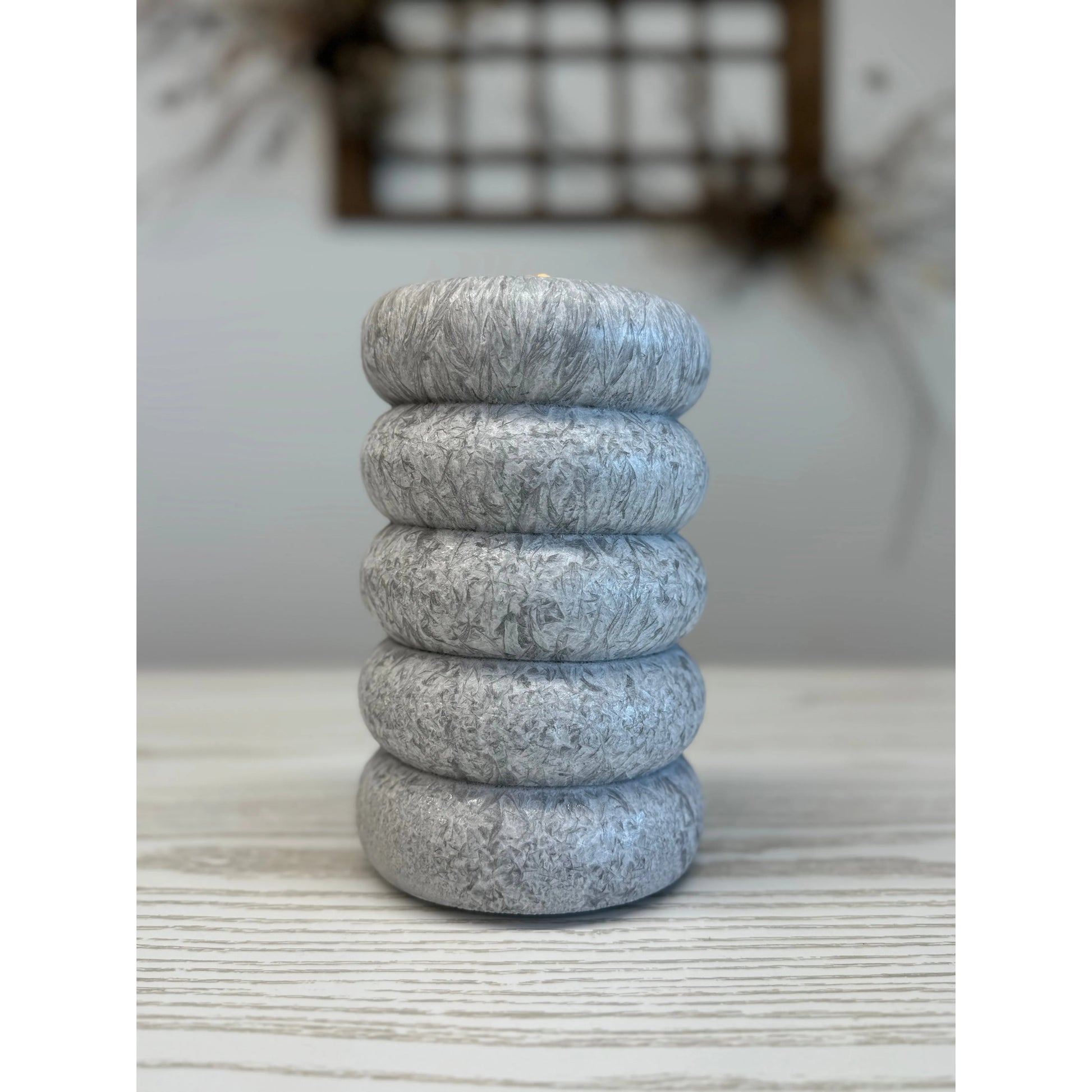 Stack of five gray stone rings on a textured surface with a blurred background