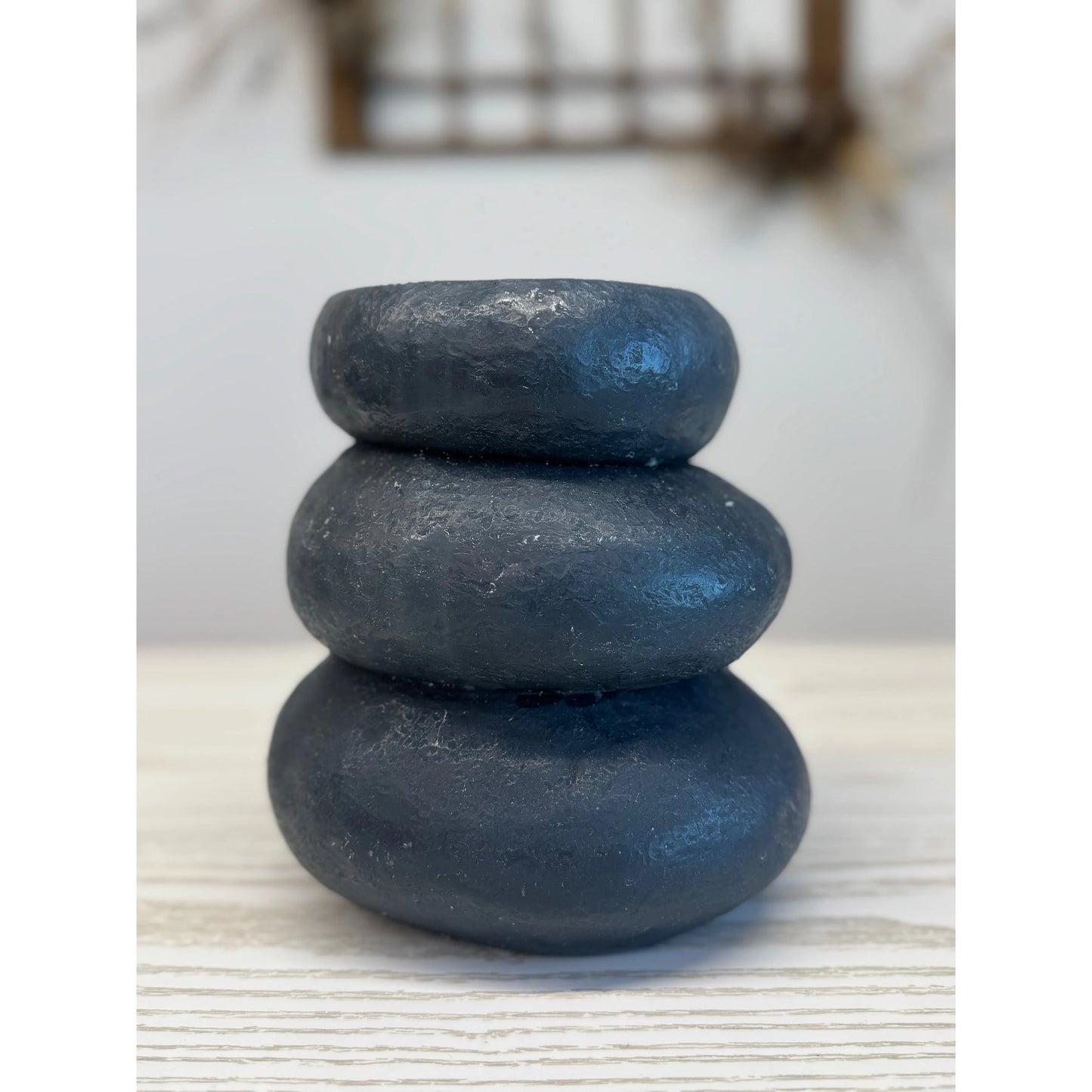 Stack of three black stones on a light surface with a blurred background
