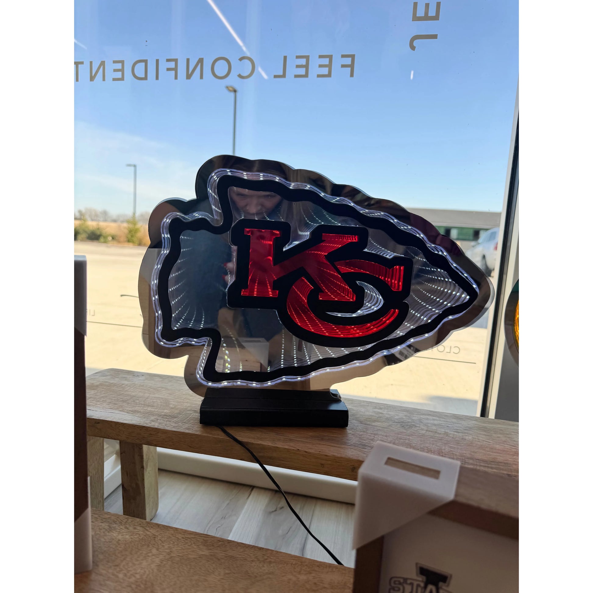 Neon sign with a Kansas City Chiefs logo on a wooden surface outdoors