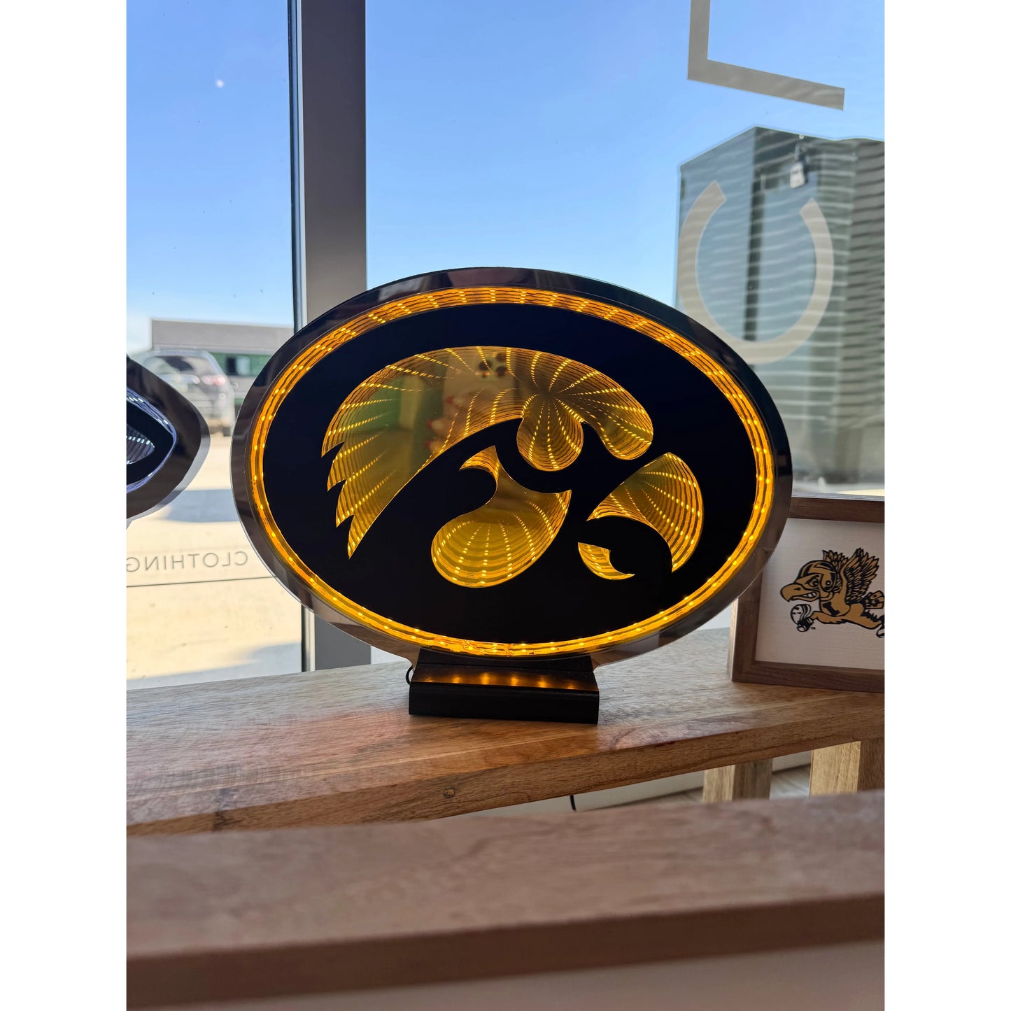 Decorative LED sign with an Iowa Hawkeye's logo on a wooden surface