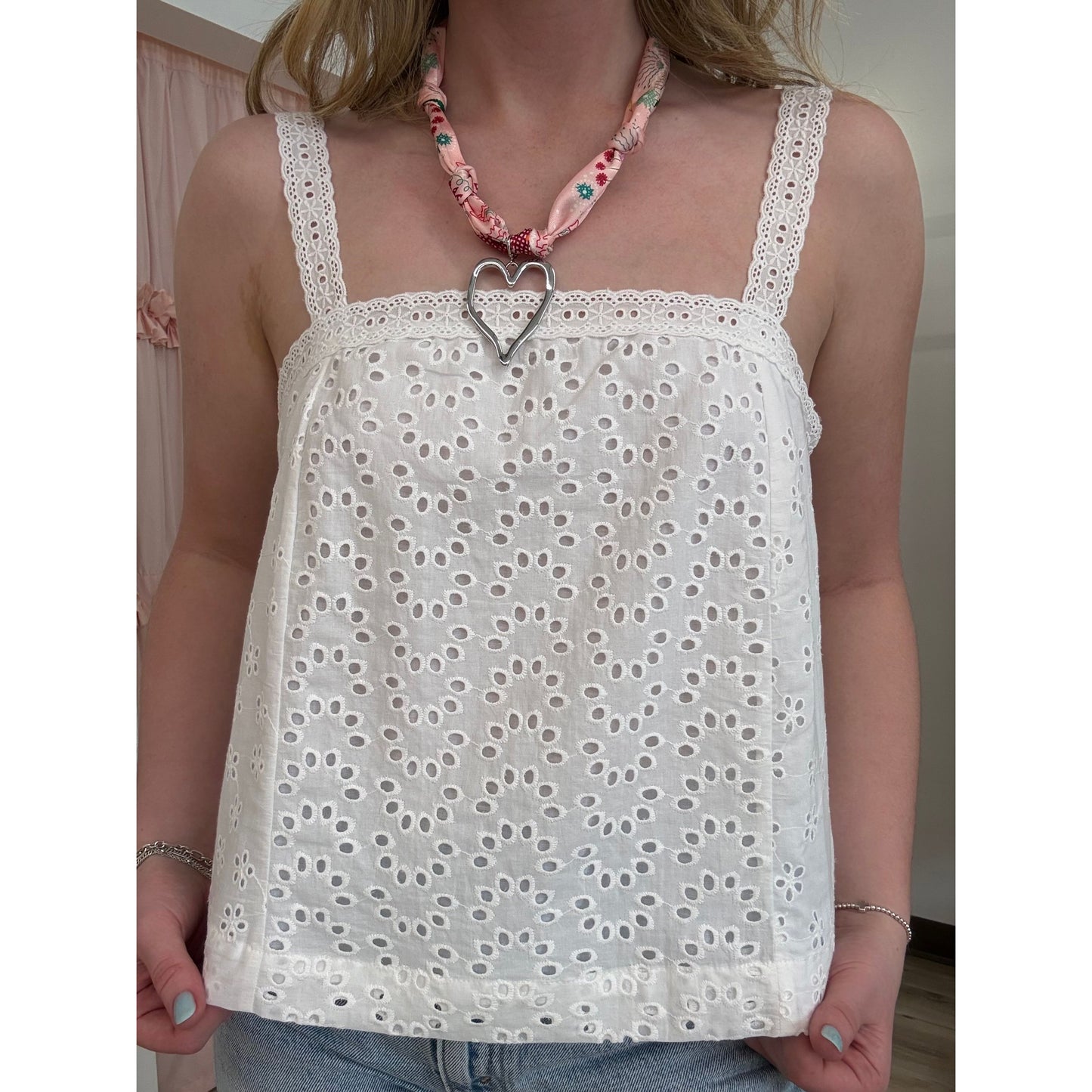 White lace top worn by a person with a pink scarf around their neck.
