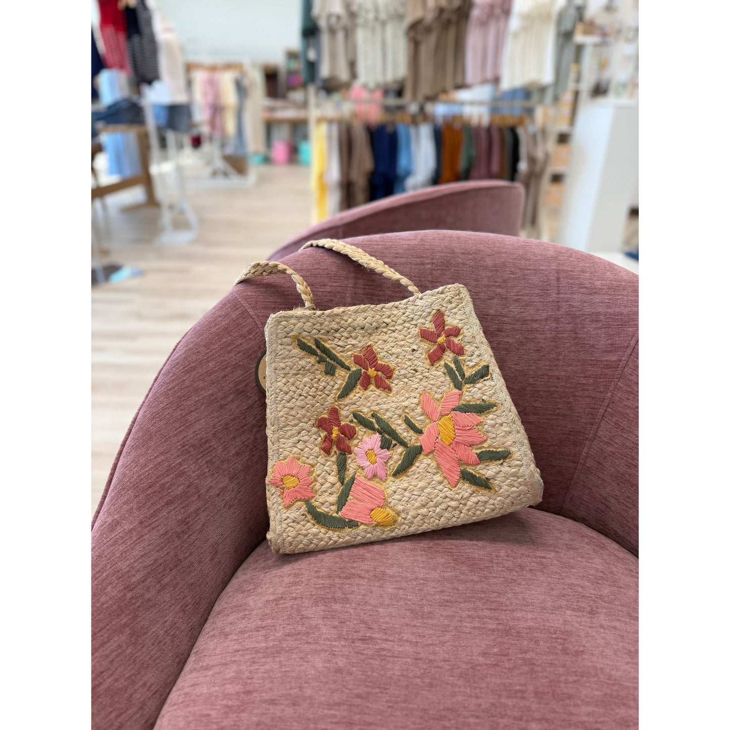 Floral embroidered bag on a pink chair in a store setting
