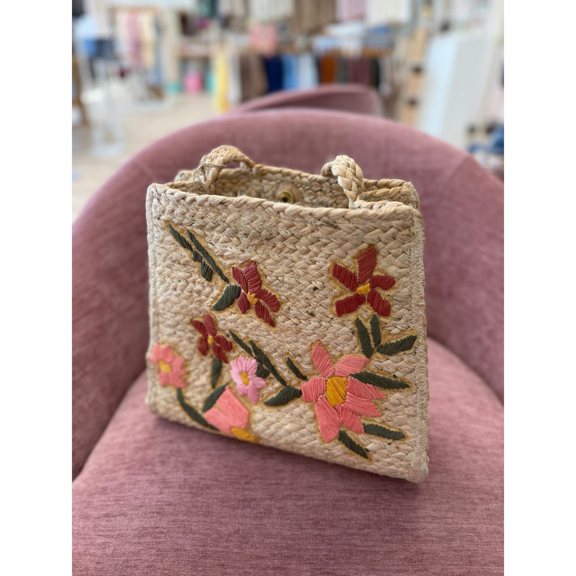 Woven handbag with floral embroidery on a pink chair
